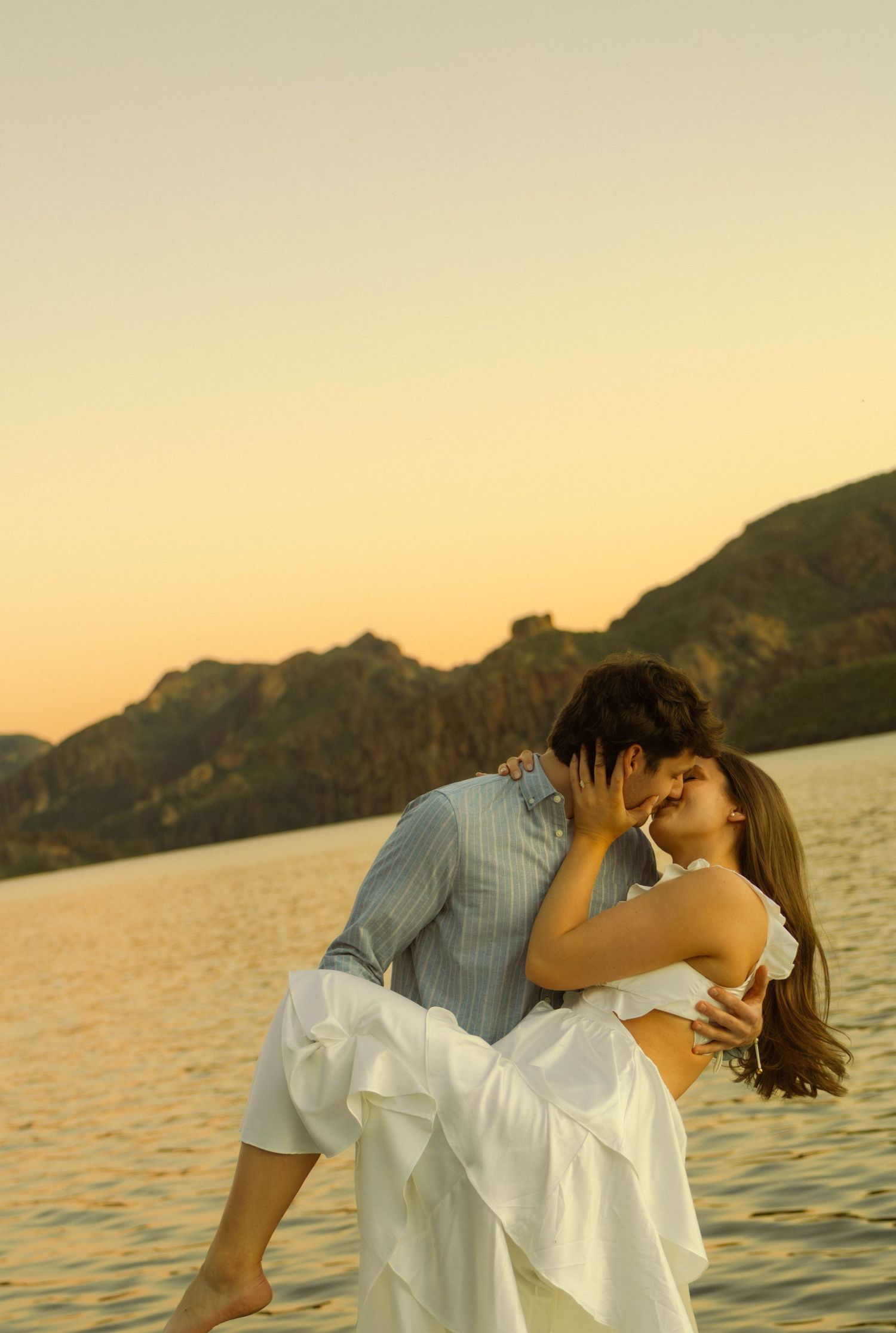 Romantic sunset moment on a dock with mountains and lake in background.