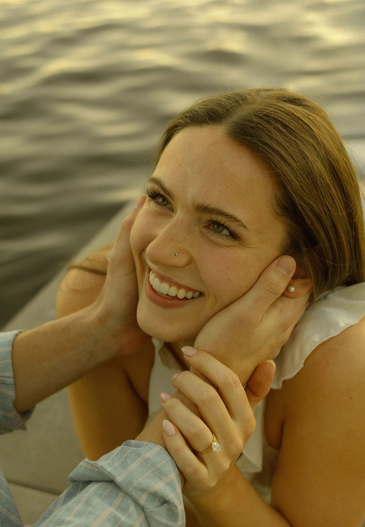 A radiant smile glows in golden sunlight by the water.