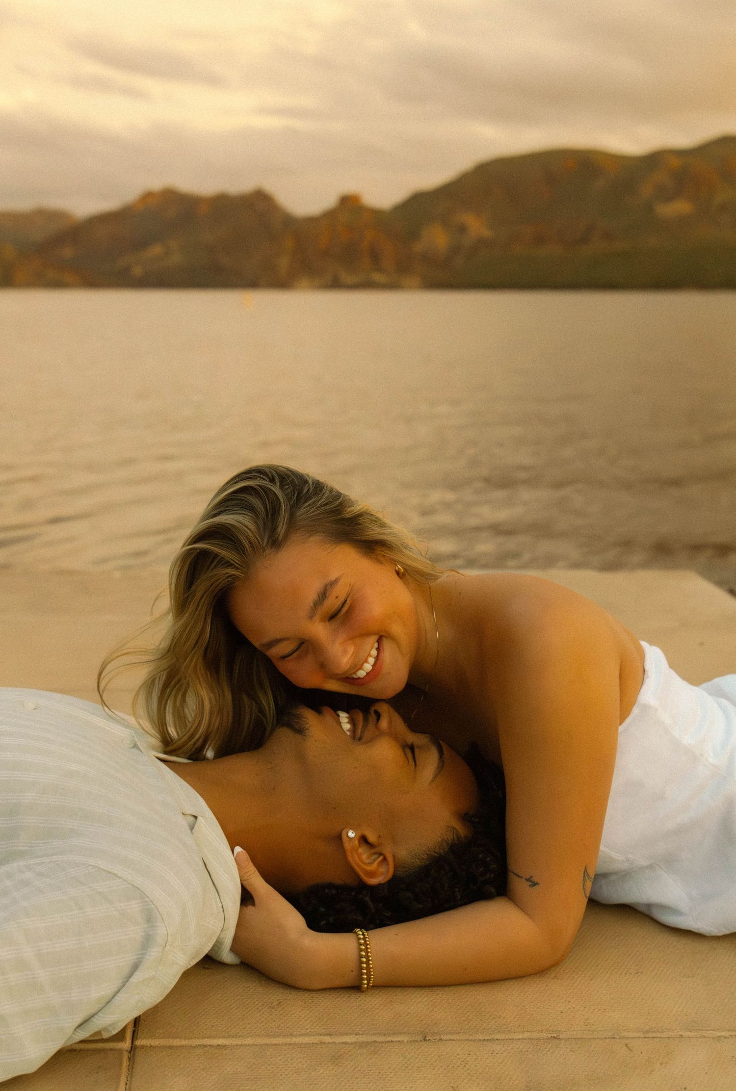 A series of photos showing a person laying down and laughing on a wooden deck by the water.
