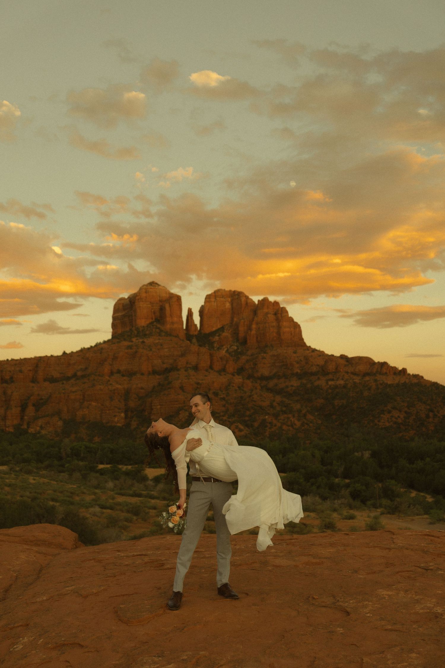 Couple shares romantic wedding moment at sunset with Cathedral Rock in Sedona, Arizona as a stunning backdrop.