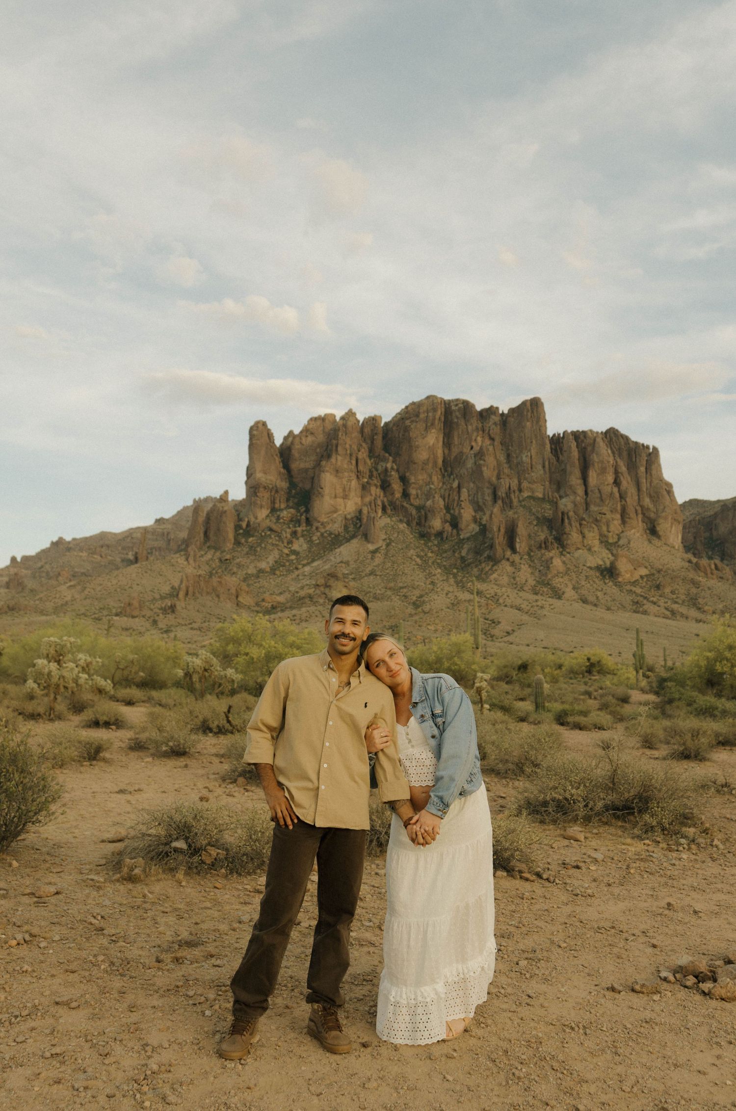 Couple poses in Arizona desert with Superstition Mountains backdrop.