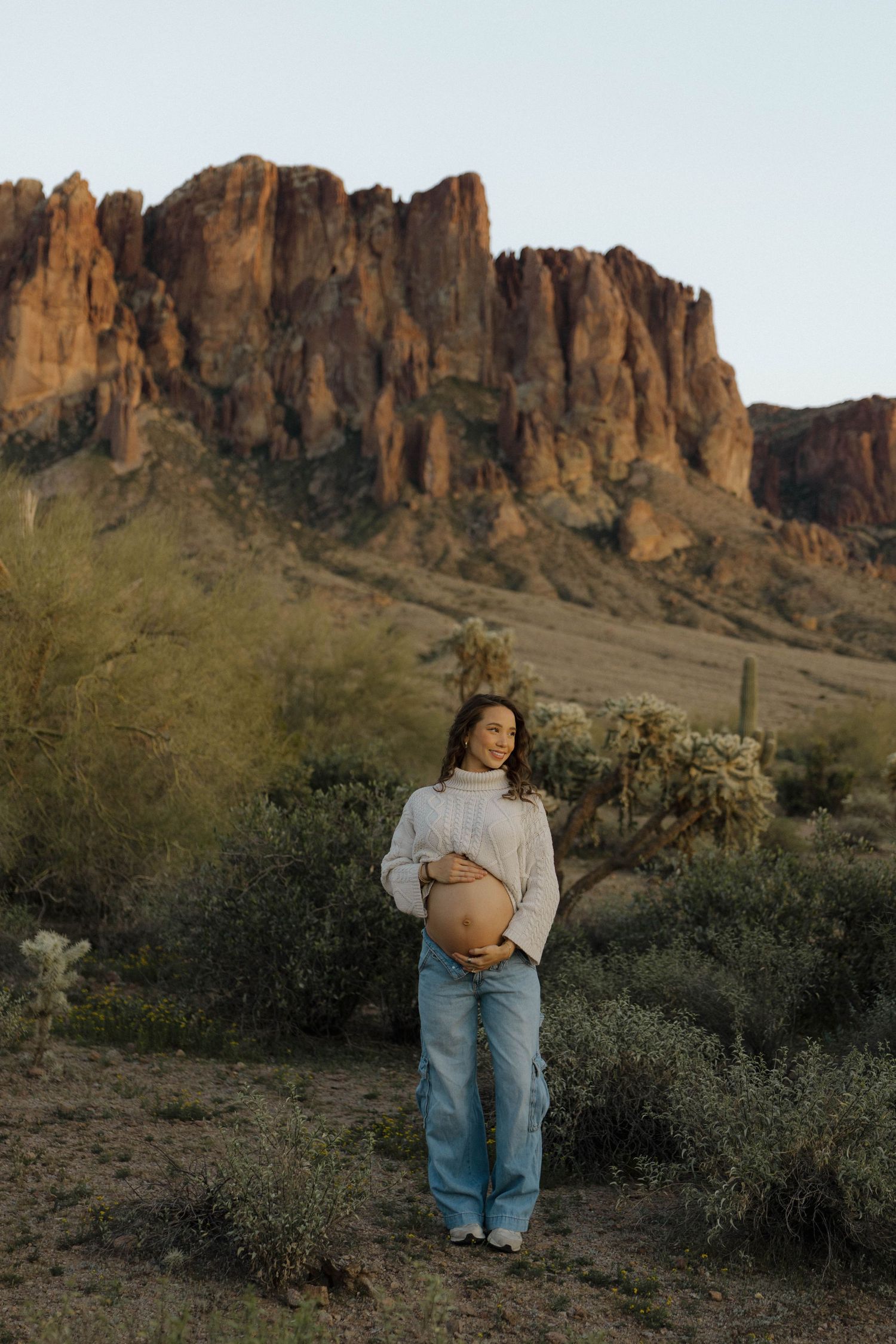 A loving couple shares an intimate moment in front of majestic desert rock formations at sunset.