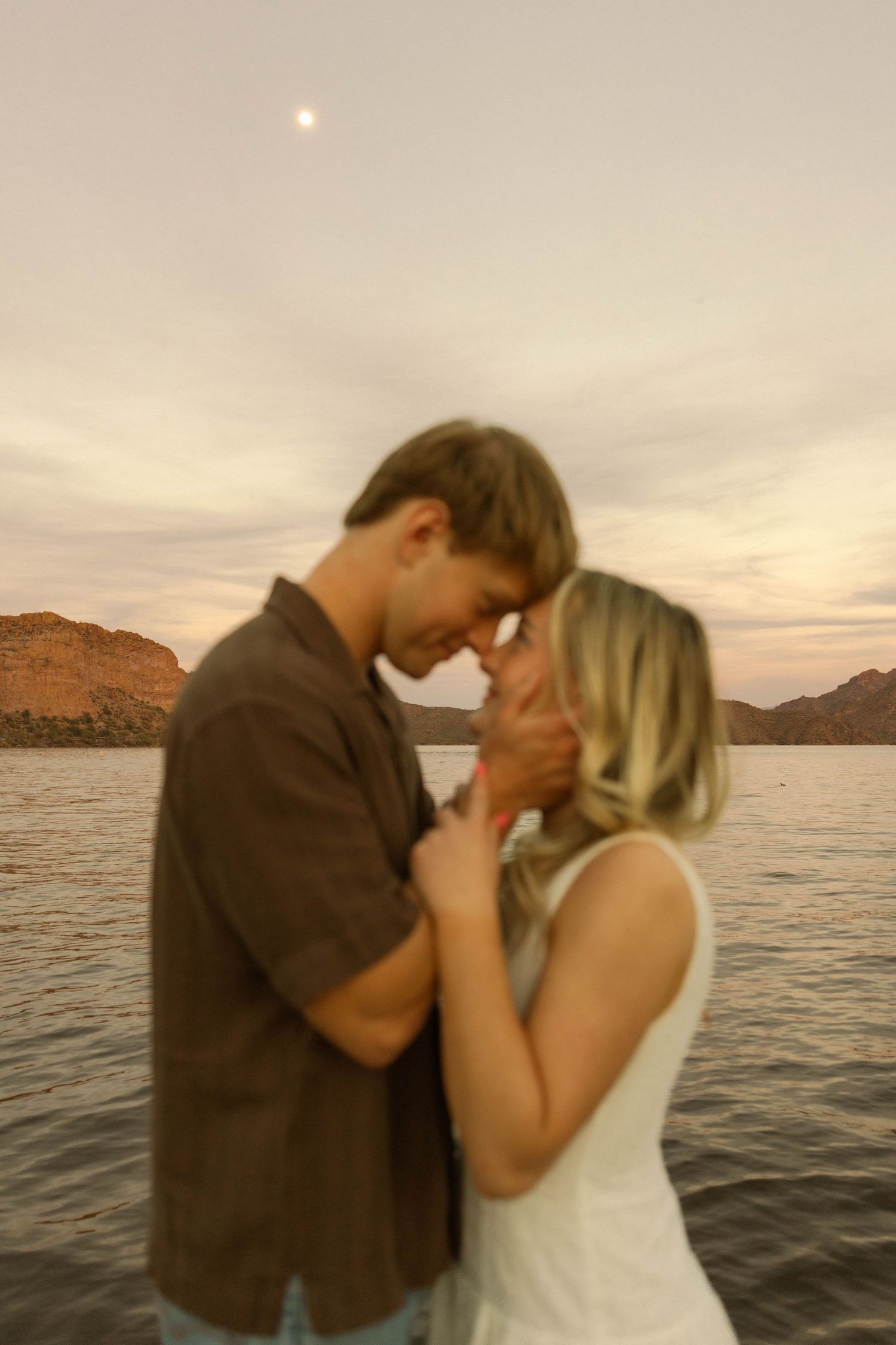 A romantic sunset moment captured against a mountainous lake backdrop.