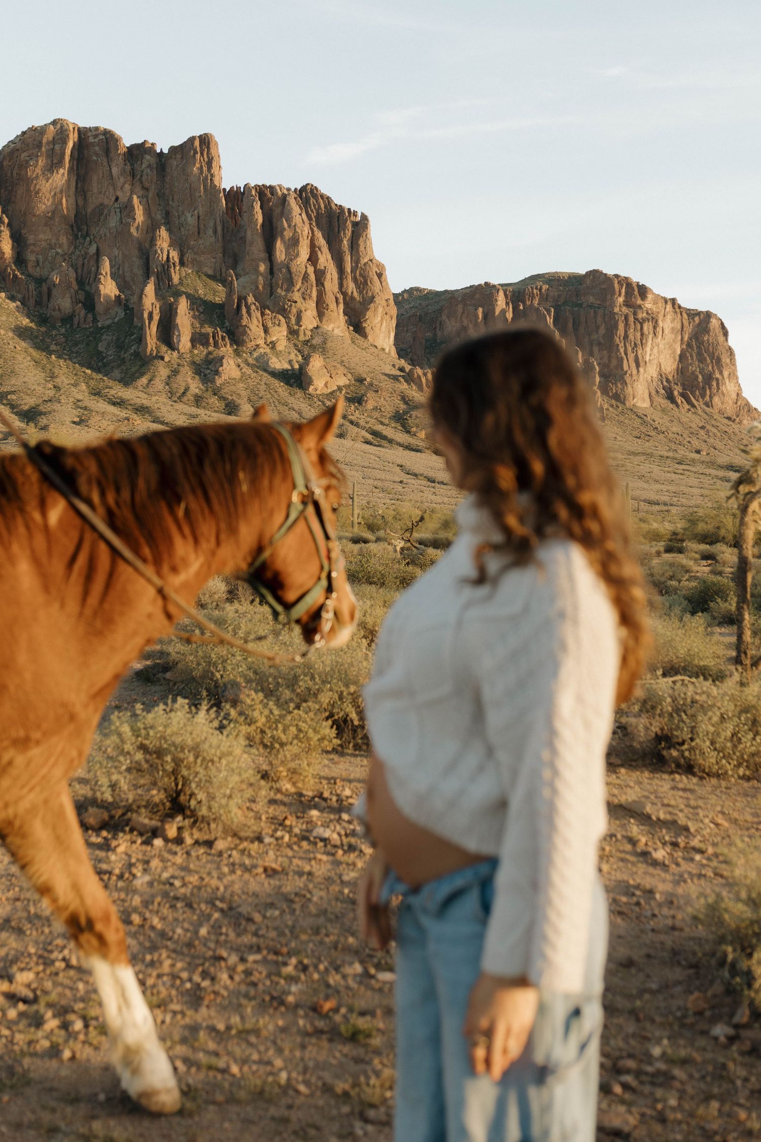 A couple shares a tender moment against a backdrop of majestic desert cliffs during golden hour.