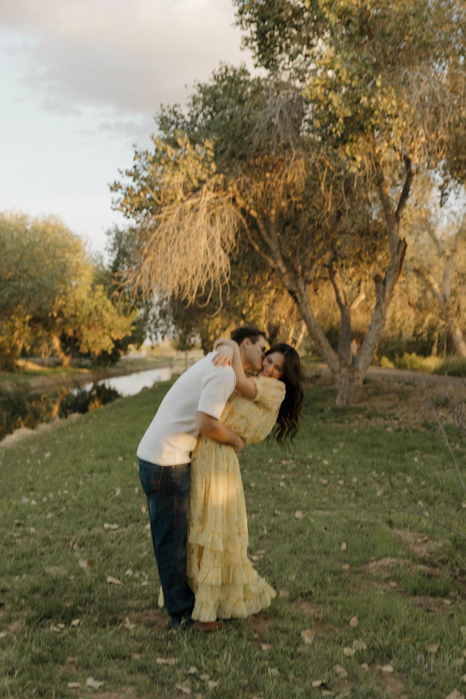 Dancing couple in yellow dress and white shirt among autumn trees.