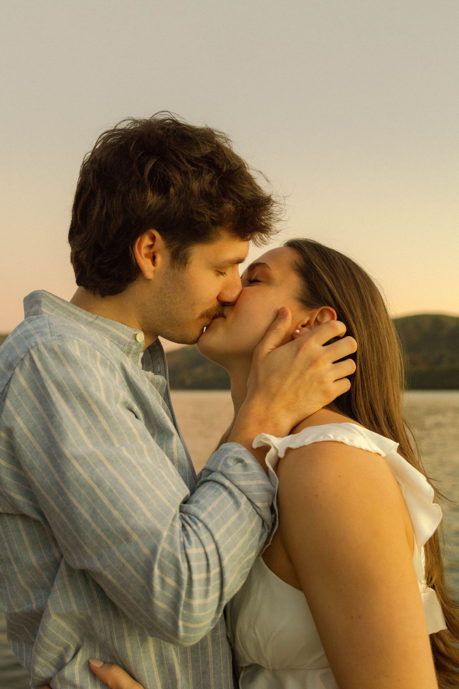 Intimate moment captured during golden hour with lake and mountains in background.