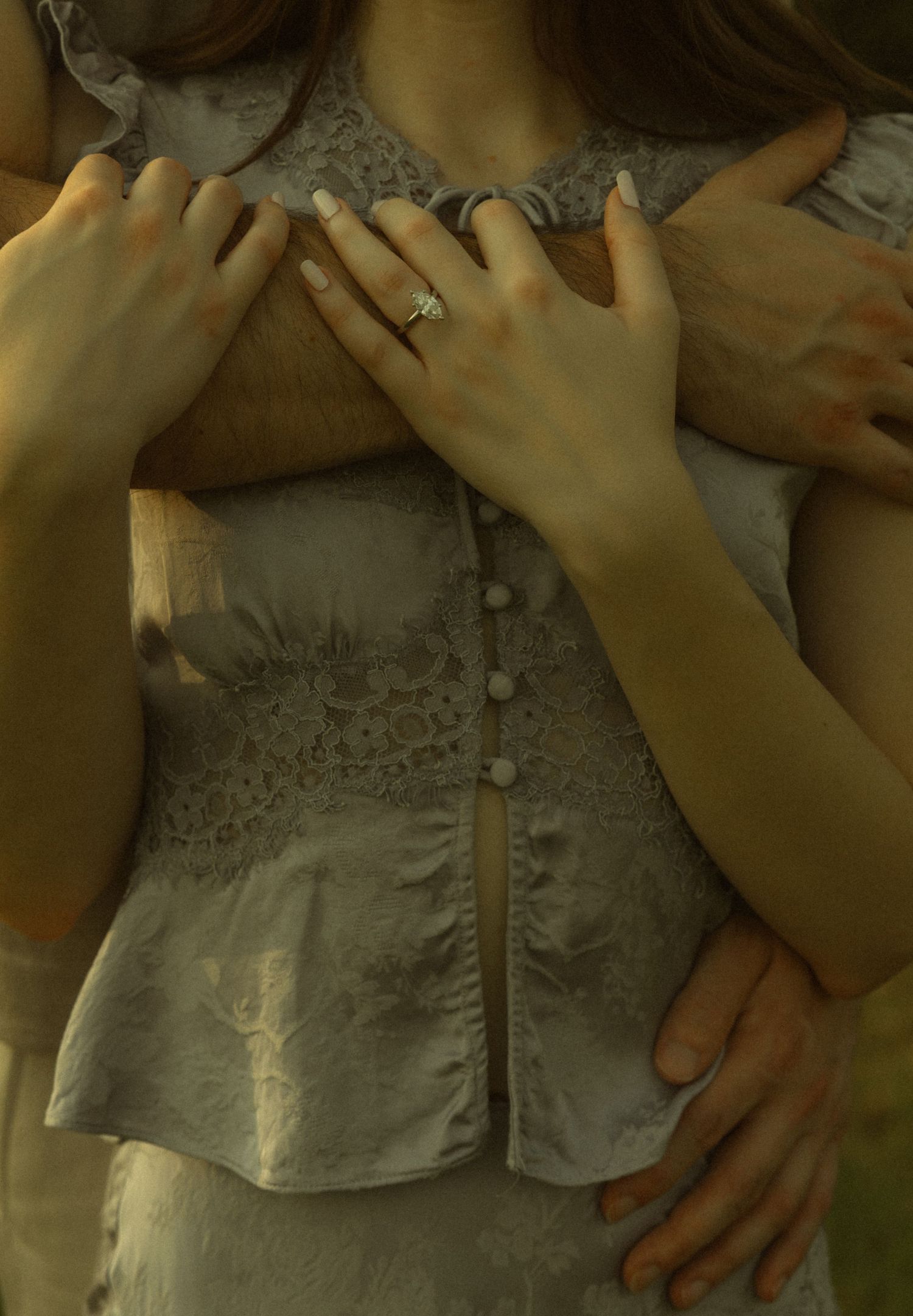 Close-up of a couple embracing, woman wearing a diamond ring on her finger.