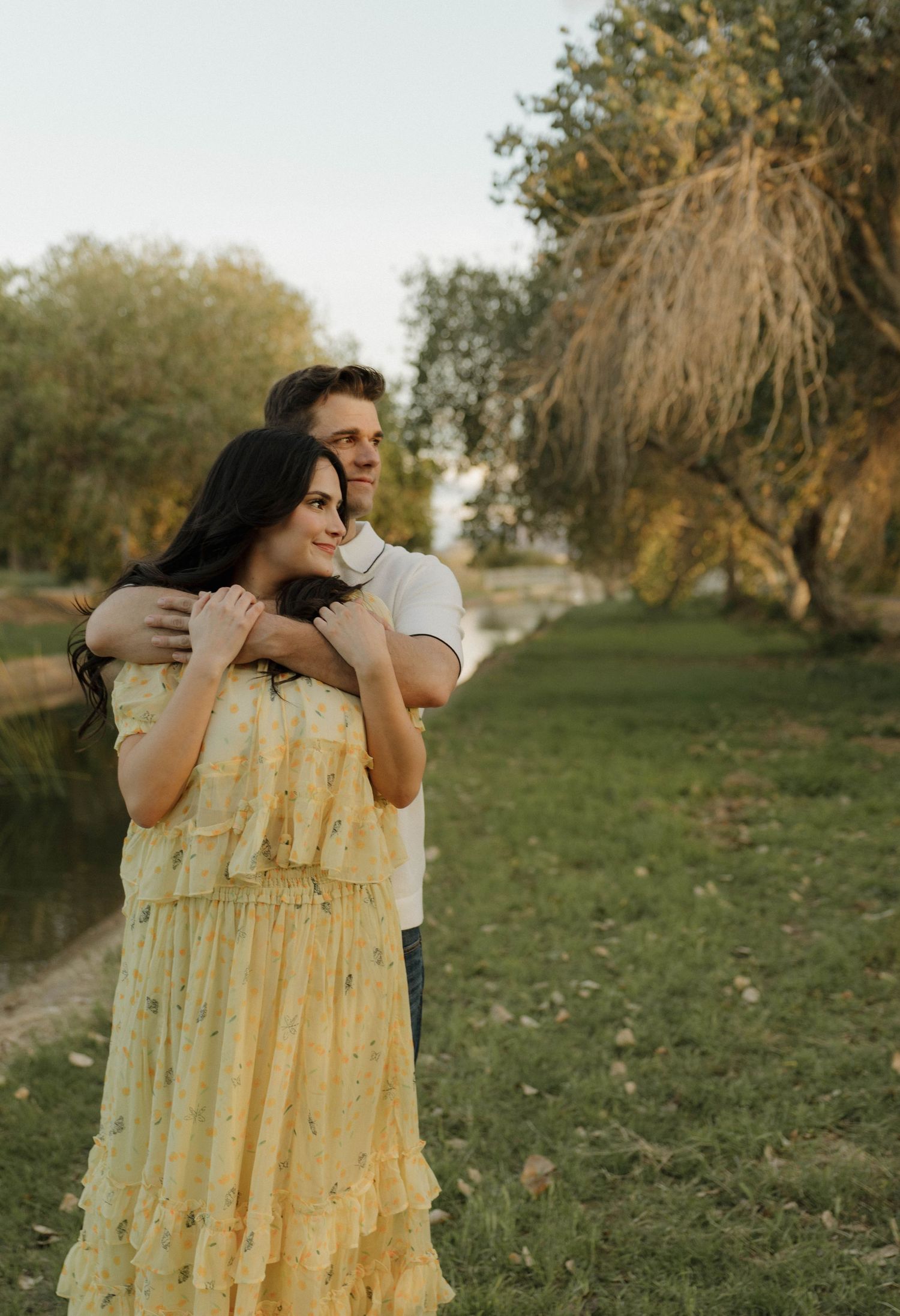 A couple embracing and sharing intimate moments in a grassy field during golden hour.
