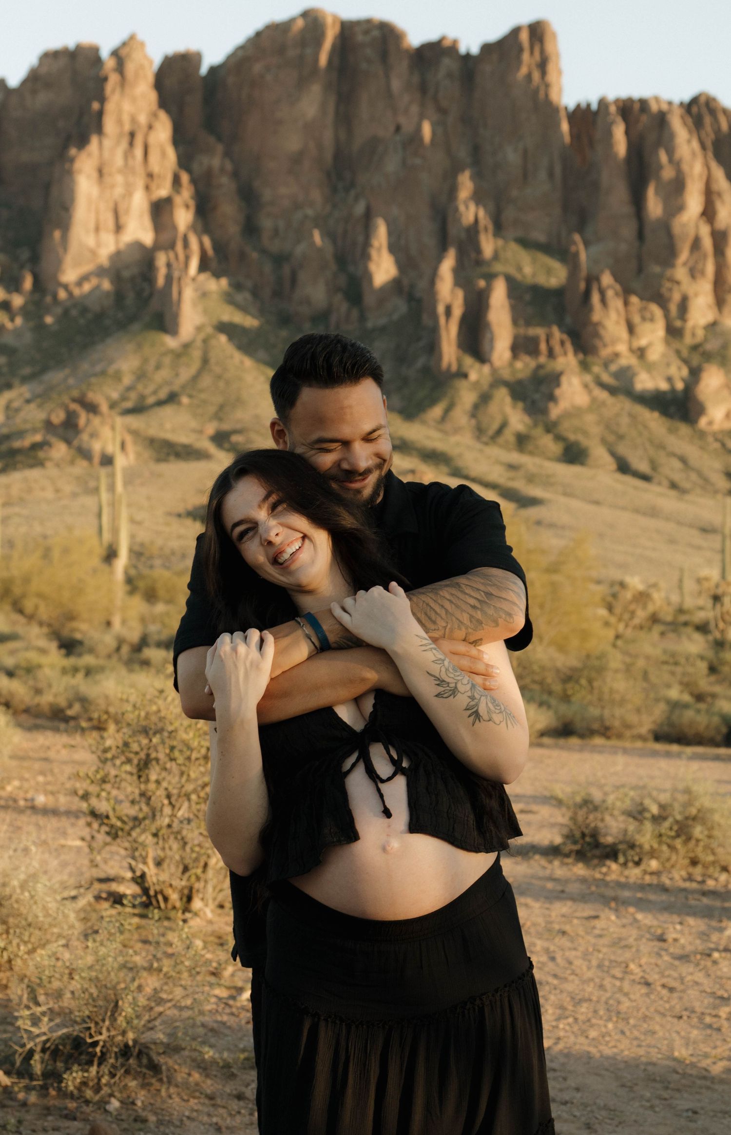 Romantic couple photoshoot in desert landscape with dramatic rock formations at sunset.