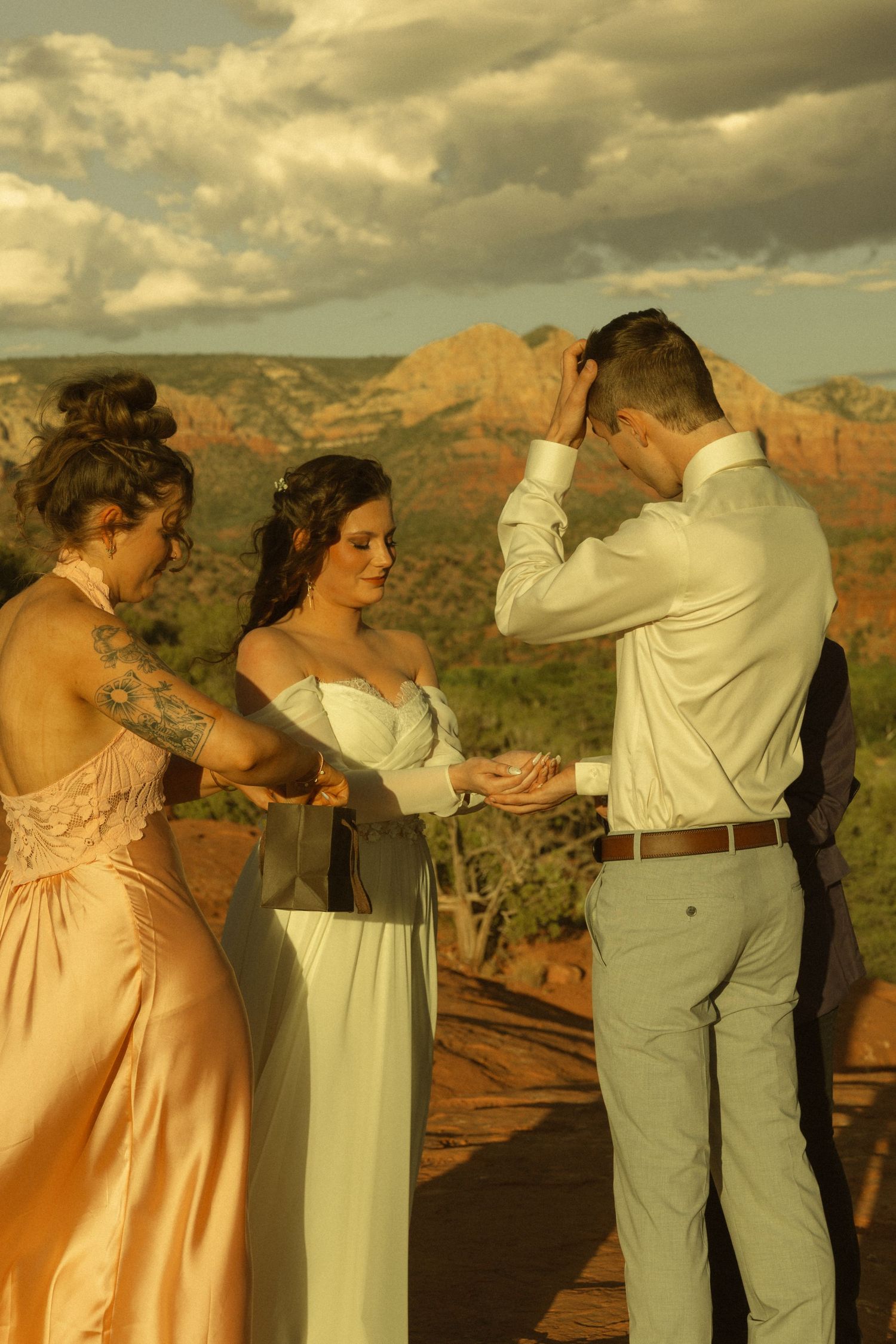 Bride and groom exchange rings at a stunning Sedona, Arizona outdoor wedding with red rock formations backdrop.