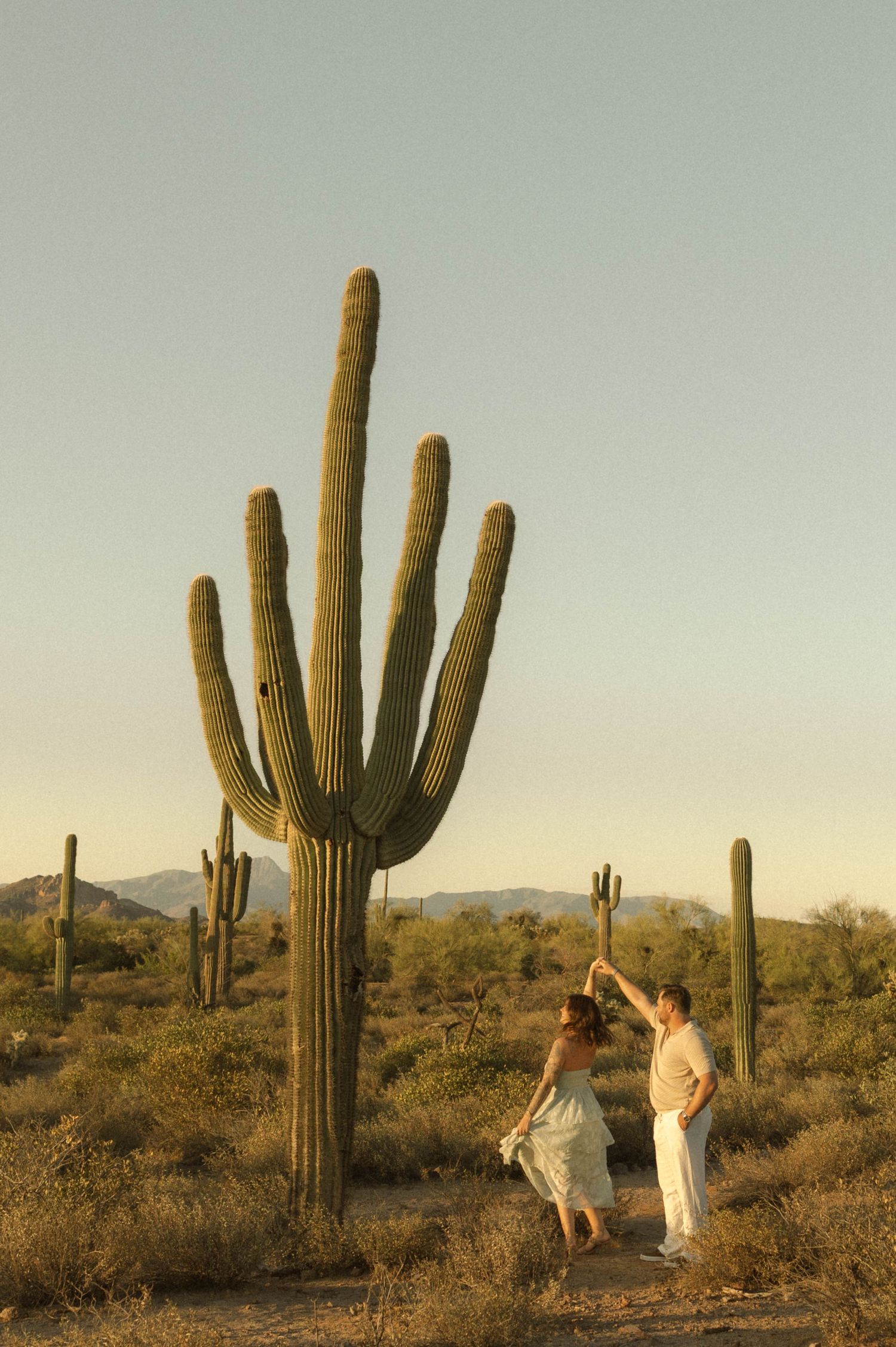 Couple dancing near a giant saguaro cactus in the Sonoran Desert at golden hour.