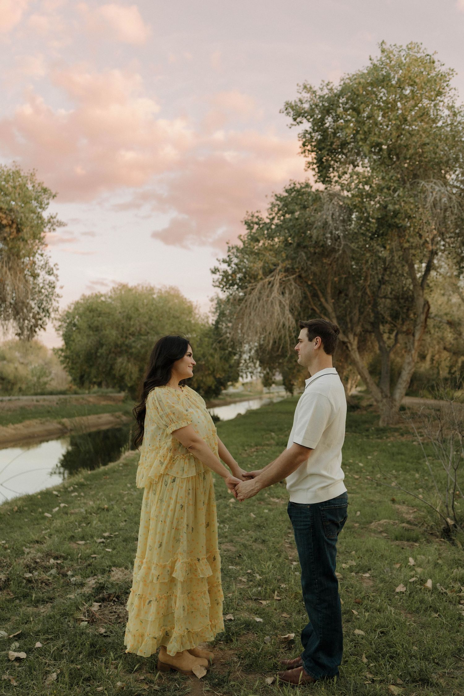 A romantic couple sharing a tender moment outdoors among trees during sunset.