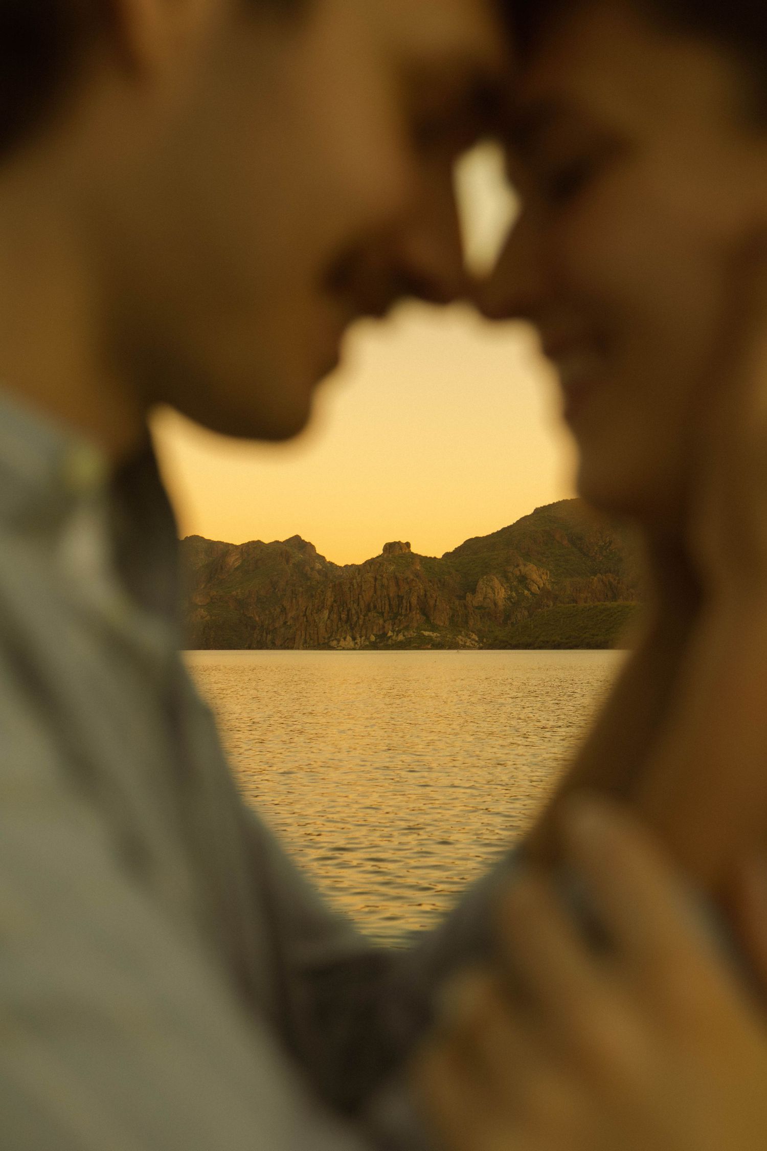 Mountain landscape framed between silhouettes at sunset by a lake.