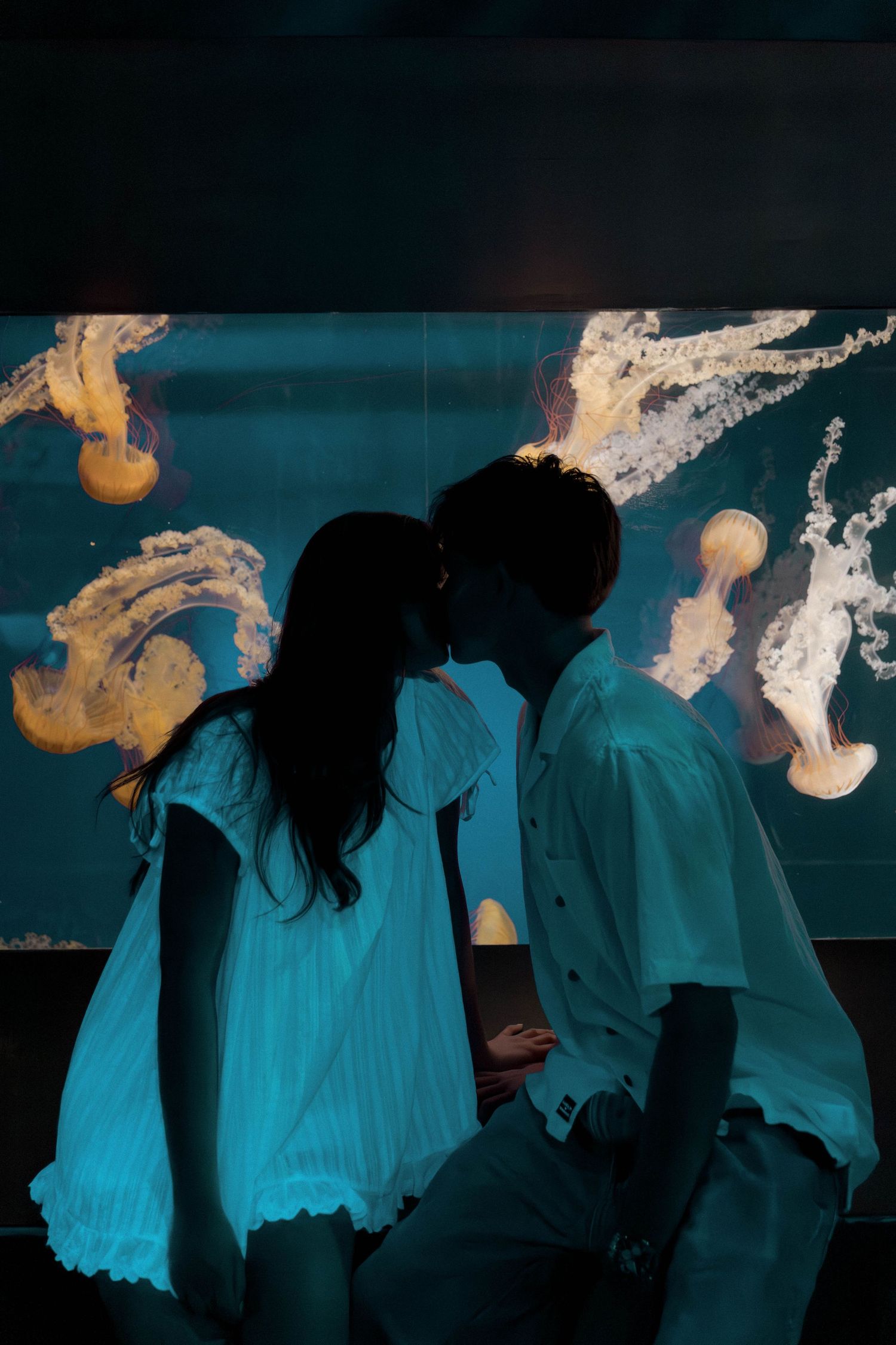 Silhouettes of people standing against a dark blue background with ethereal lighting effects.