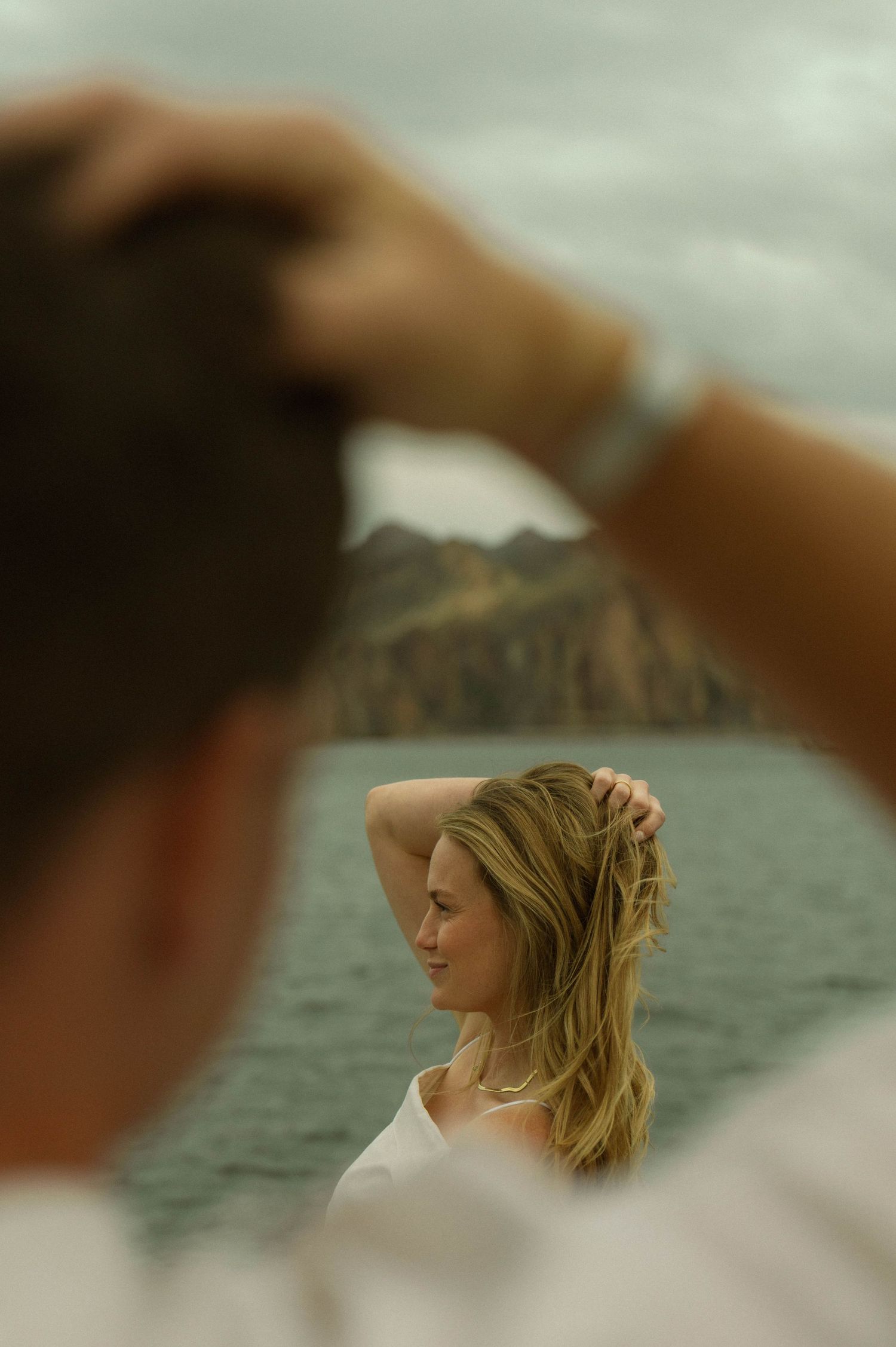 Scenic ocean view with mountains and cliffs in the background while someone gazes out at the landscape.