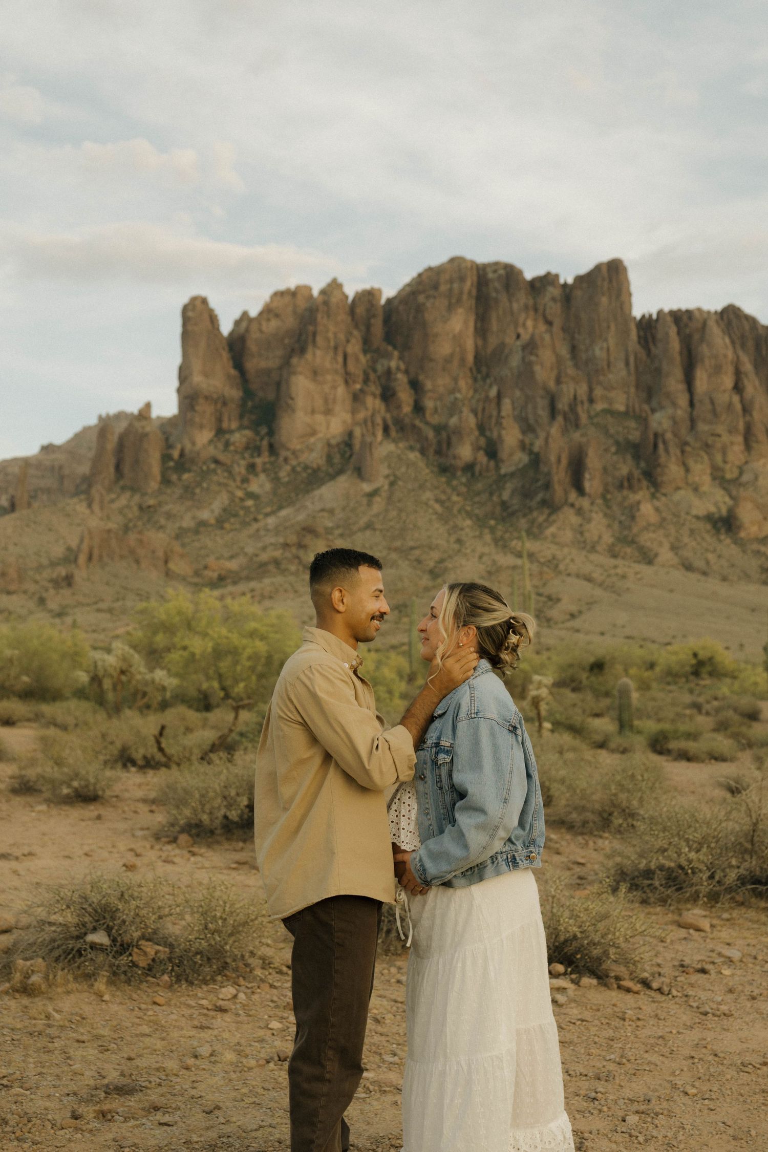Couple sharing a romantic moment in the Arizona desert with Superstition Mountains backdrop.