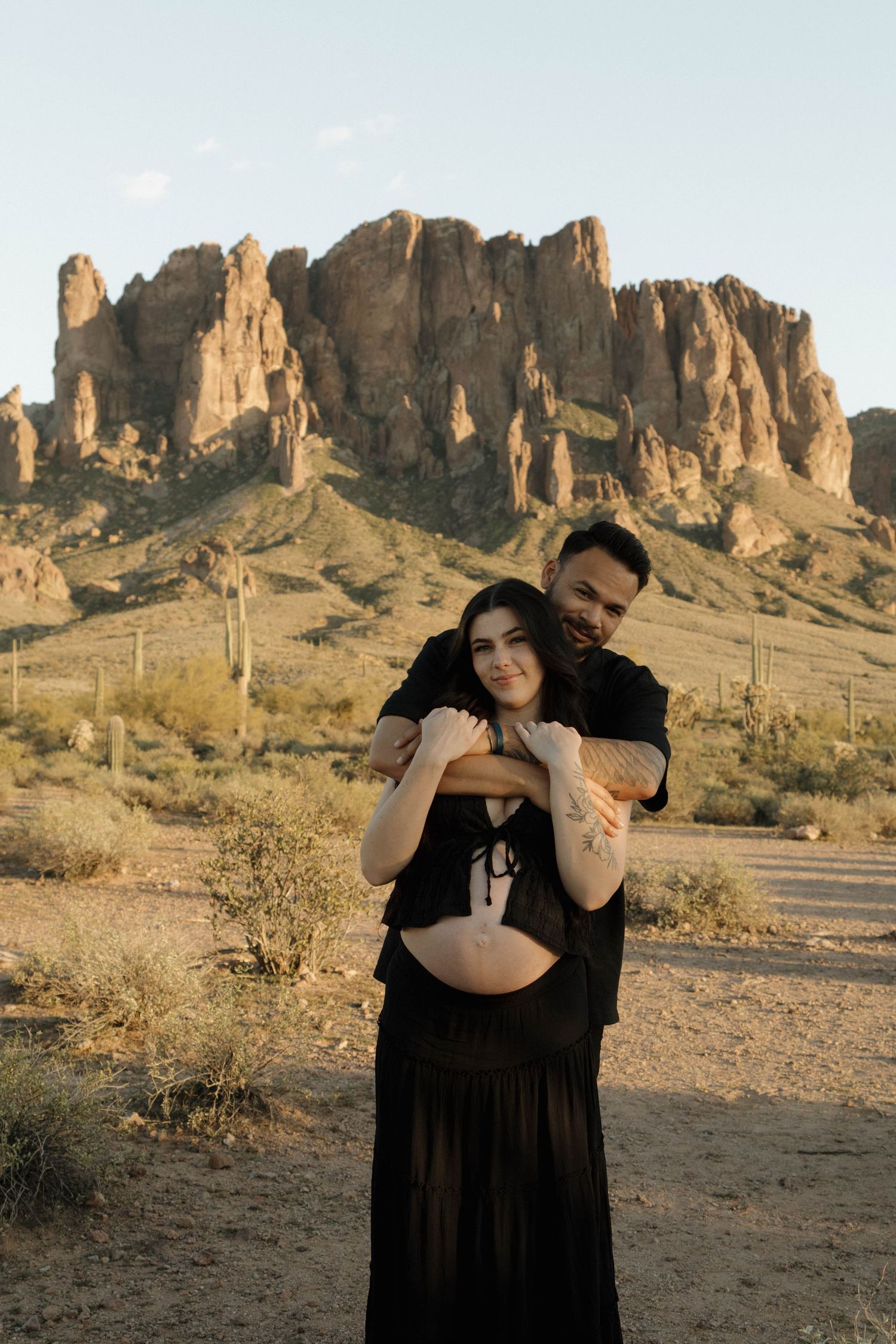 A series of maternity photos in front of desert rock formations at sunset showing a flowing black dress.