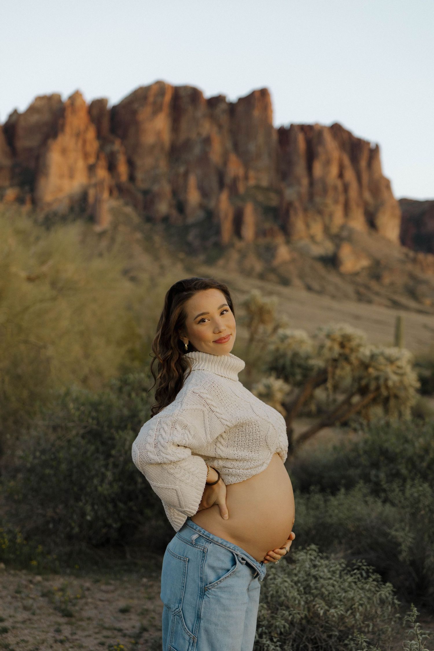 A maternity photo showcasing a baby bump against desert mountain scenery.