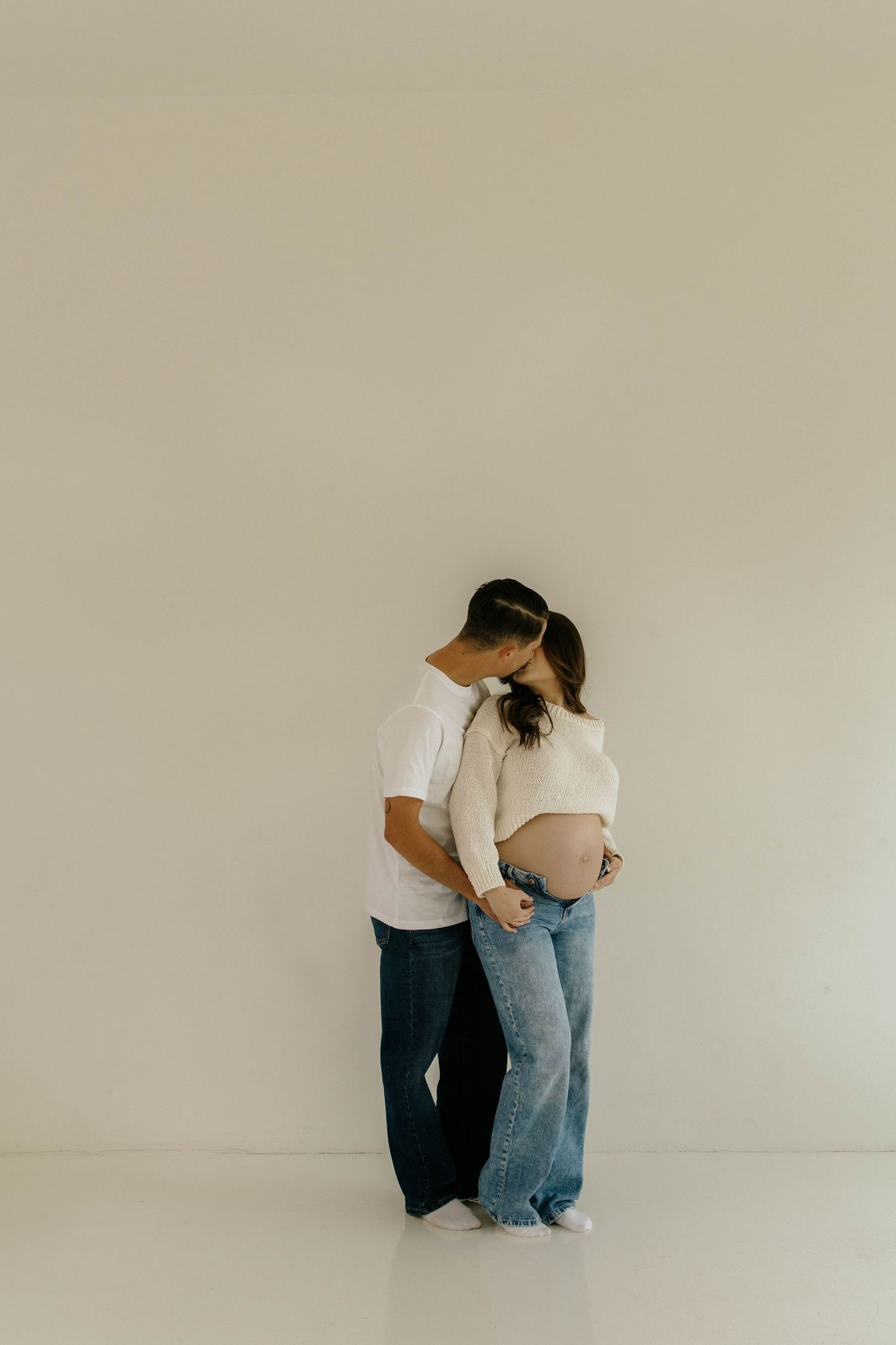 A minimalist series of photographs showing a couple in casual clothing standing against a plain wall.