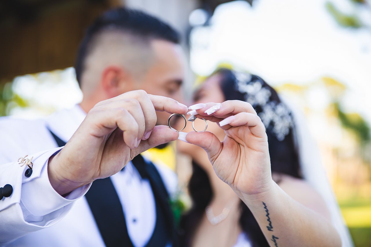 Close-up shot of hands exchanging wedding rings during an outdoor ceremony.
