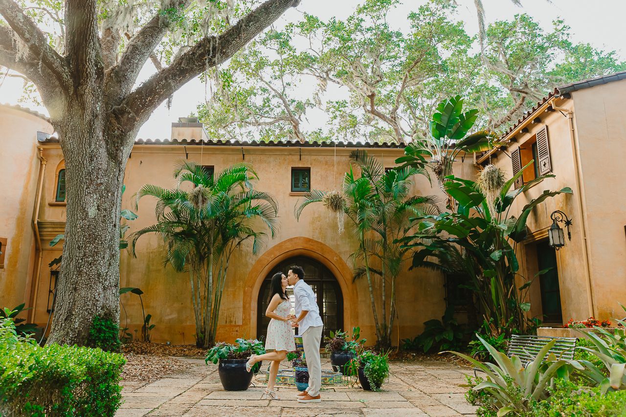 Elegant Mediterranean-style courtyard with arched doorway, palm trees and terra cotta walls creates romantic ambiance.