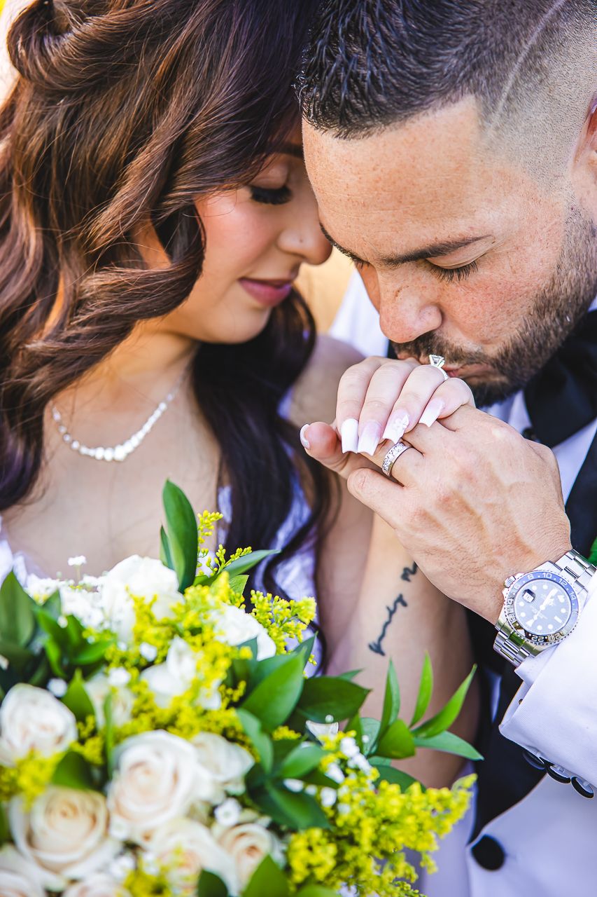 Intimate wedding moment captured with white rose bouquet and elegant jewelry details.