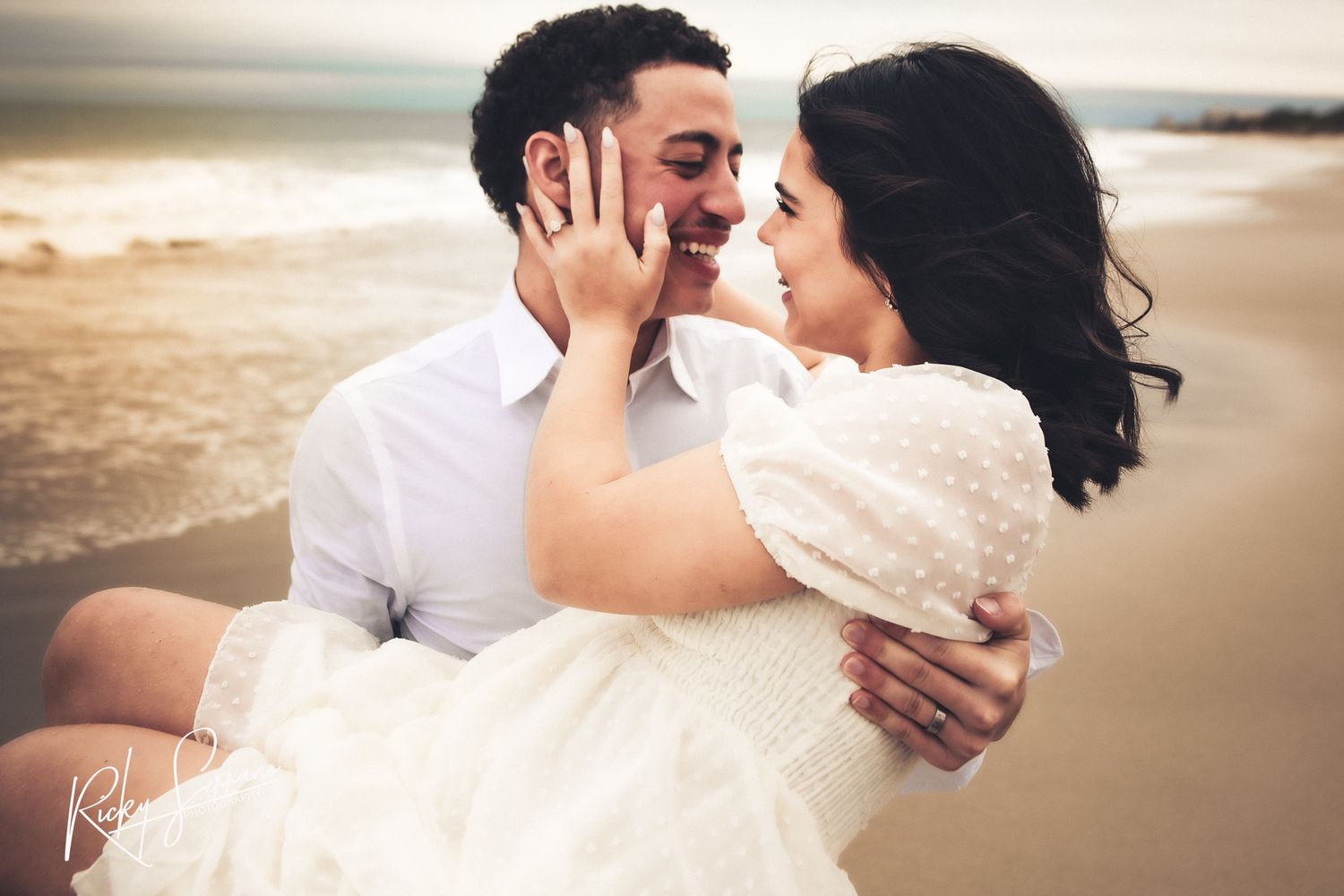 A romantic embrace on the beach with a couple in wedding attire during golden hour.