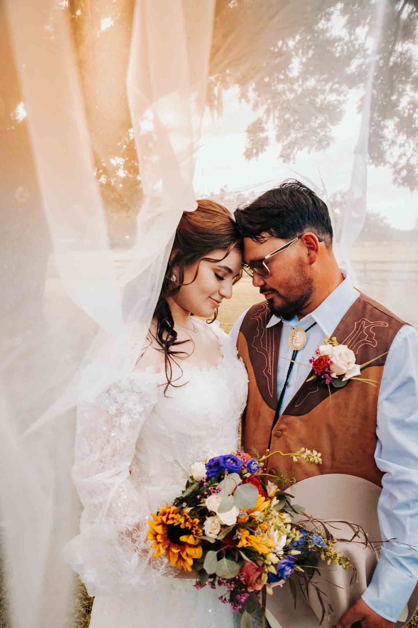 Intimate wedding portrait with colorful wildflower bouquet and soft lighting.