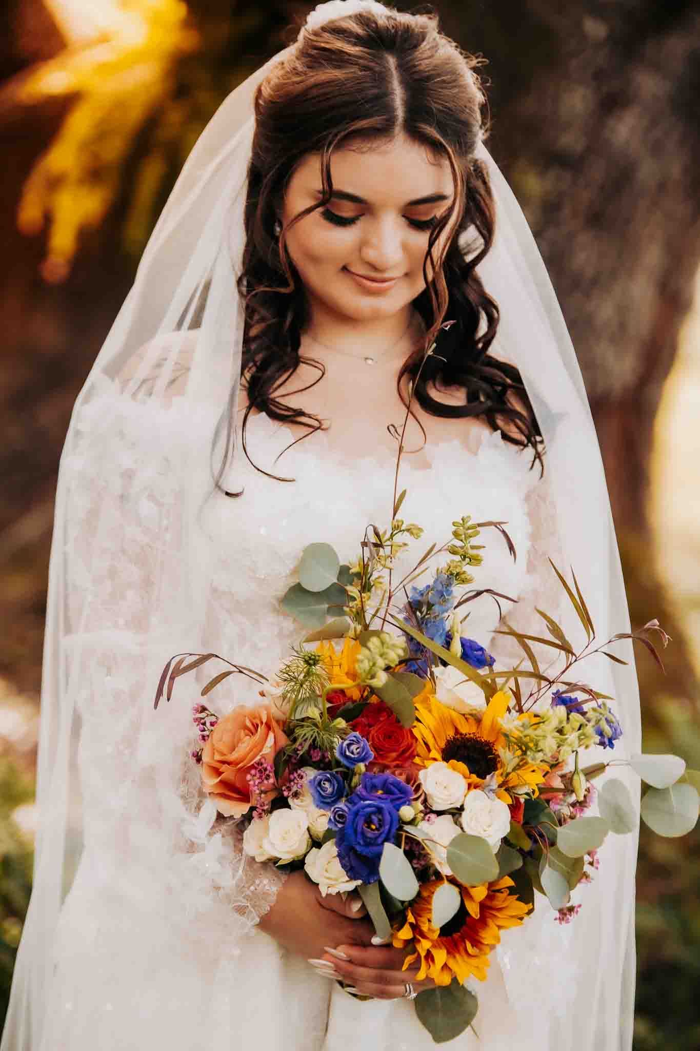 Bridal portrait featuring vibrant autumn bouquet with sunflowers and blue roses.