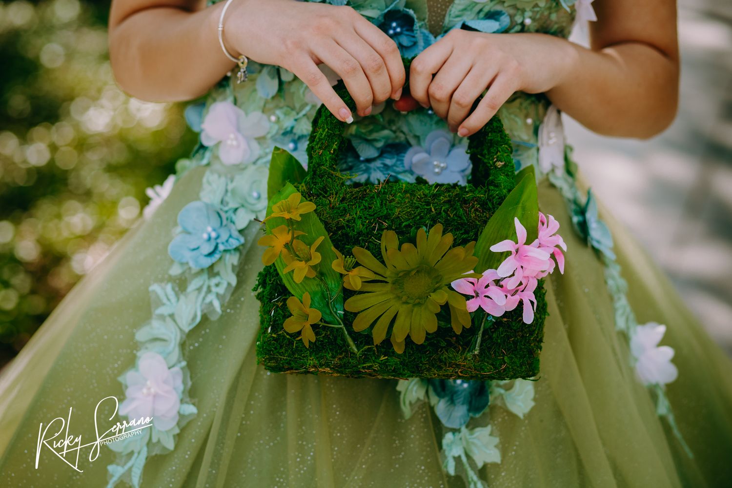 A green tulle dress adorned with delicate blue hydrangeas and yellow daisies creates a whimsical garden-inspired look.