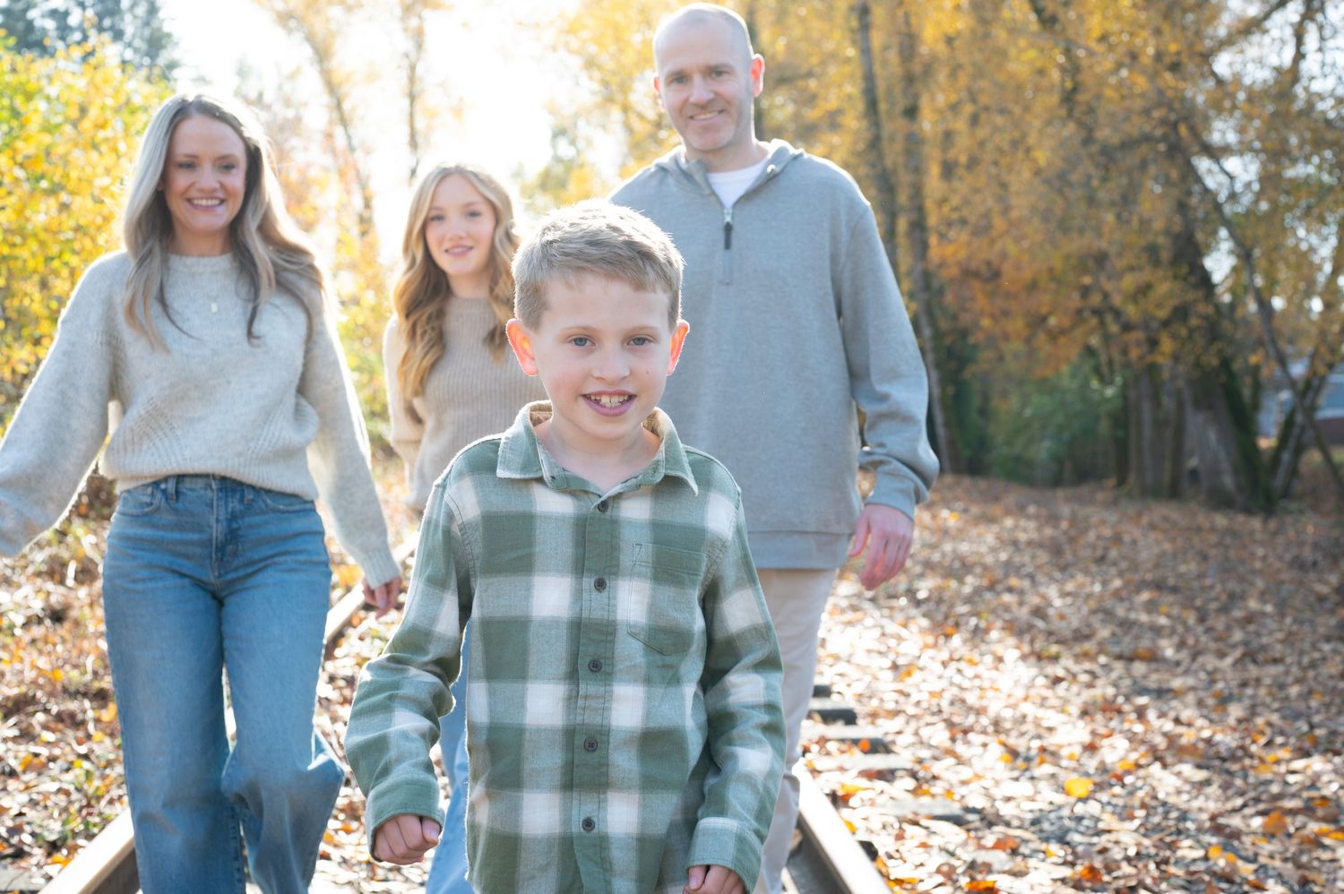 People walking and laughing together on a sunlit autumn forest trail. Family session. Portrait photography. Oregon.