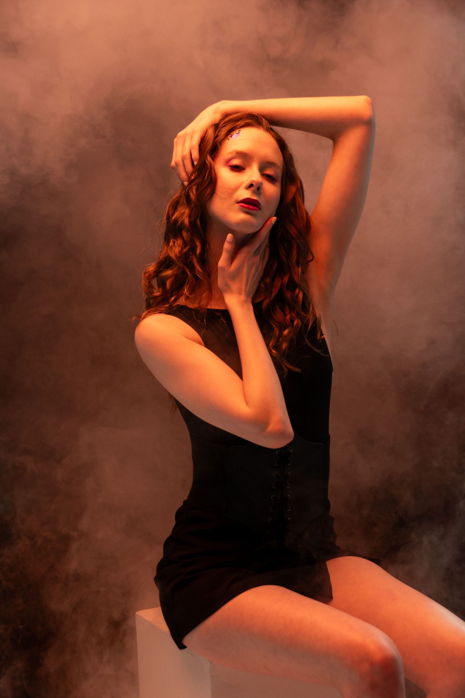 Artistic portrait series with orange lighting and smoke effects creating moody atmosphere. Creative portfolio. Studio. Portrait photography.