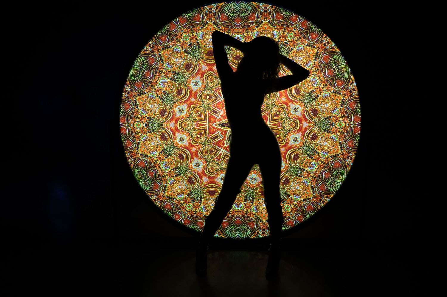 Dancing silhouette performs against large circular mosaic pattern background. Hopscotch. Portrait Slam.