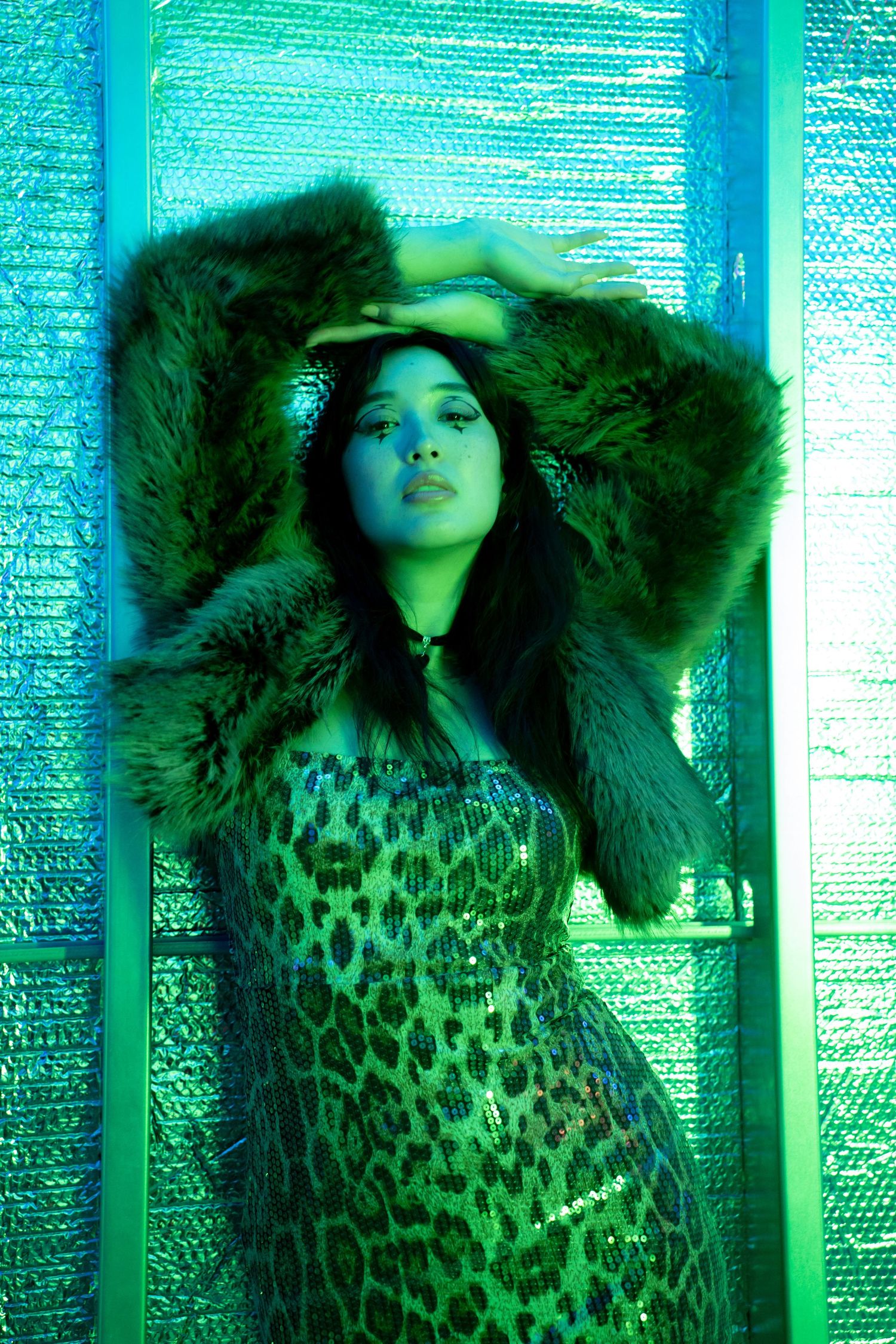 Figure in leopard print and fur poses against turquoise metallic backdrop. Hopscotch. Portrait Slam.