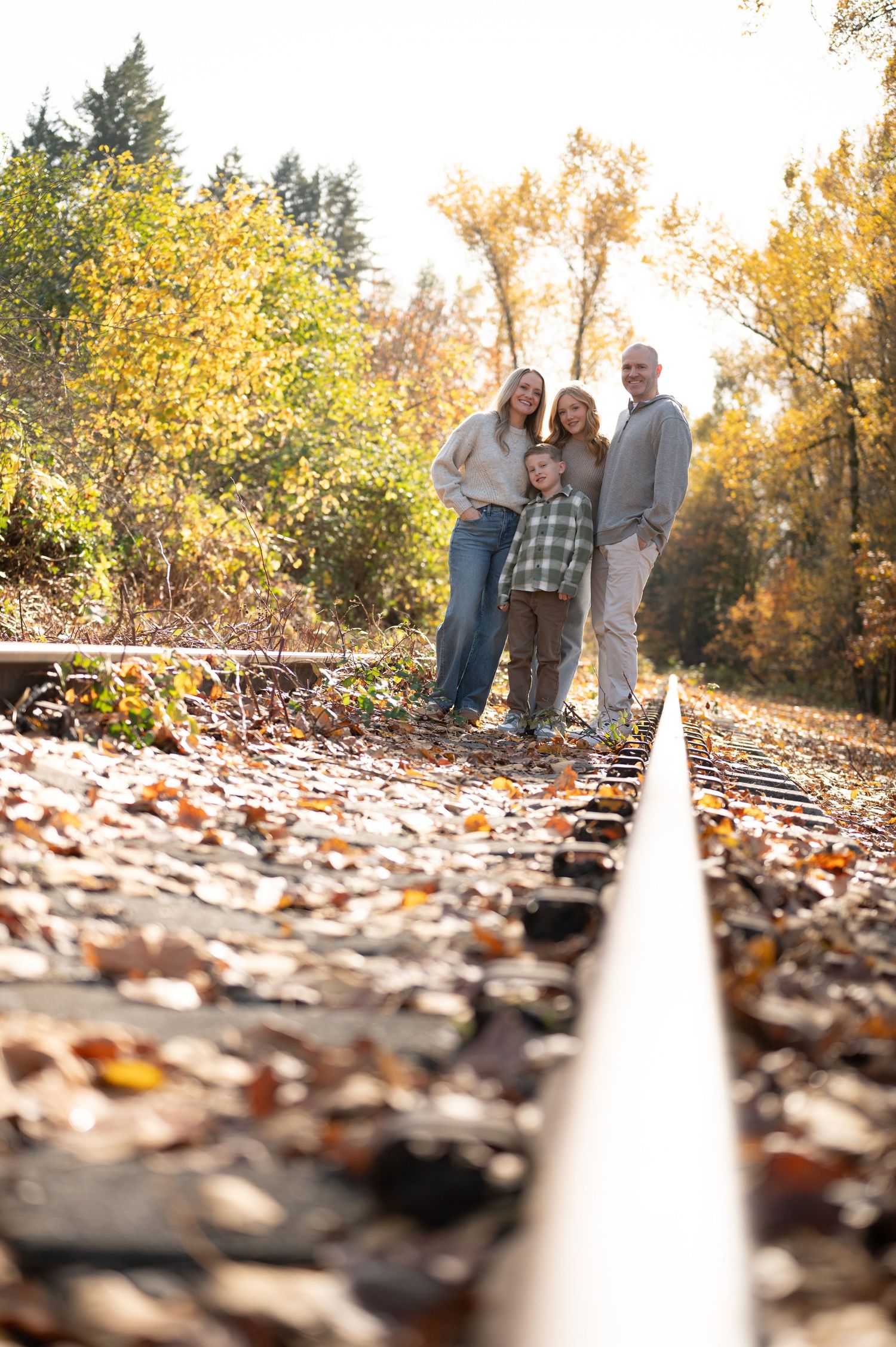 Creative low-angle shot of people standing on a trail covered in fallen leaves. Family session. Portrait photography. Oregon.
