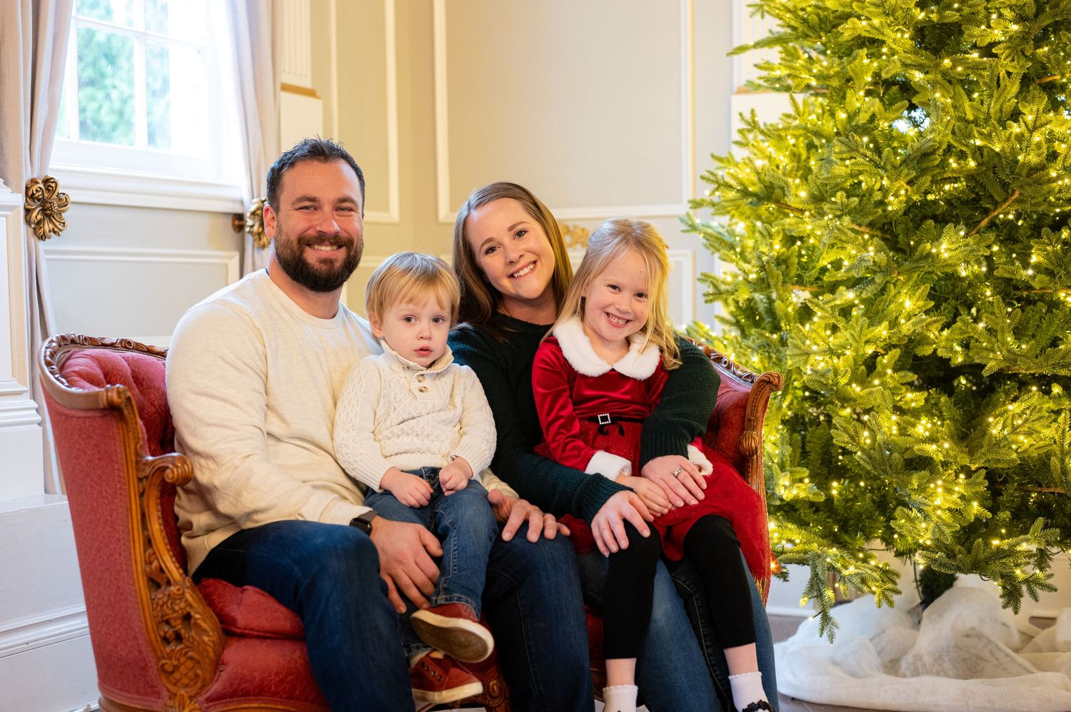 Family relaxing together on couch with decorated Christmas tree in background. Family session. Portrait photography. Oregon.