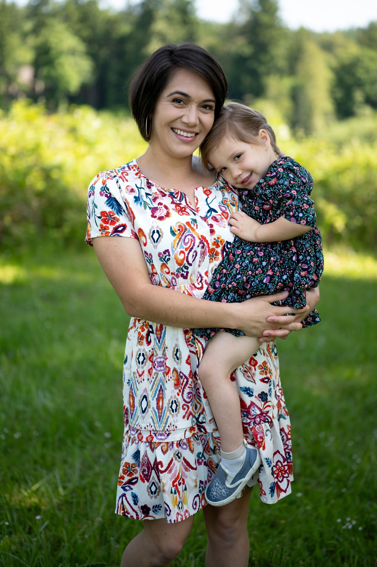 Playful outdoor portrait series showing affectionate moments in floral summer dresses.