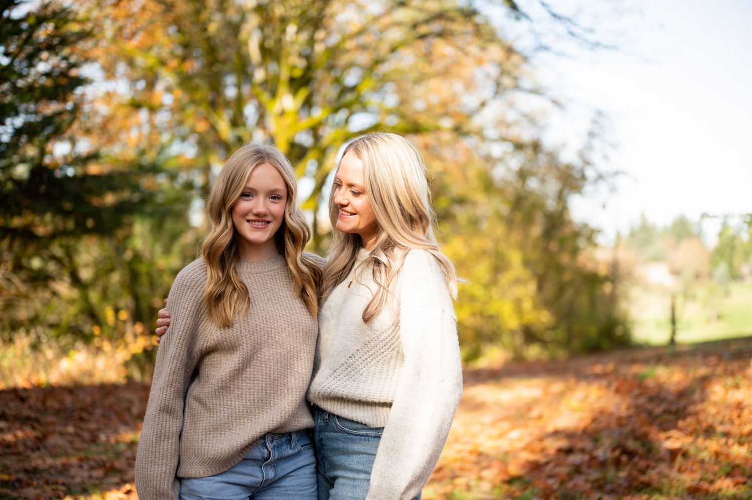 Two people walking together on a scenic fall path surrounded by colorful autumn foliage. Family session. Portrait photography. Oregon.