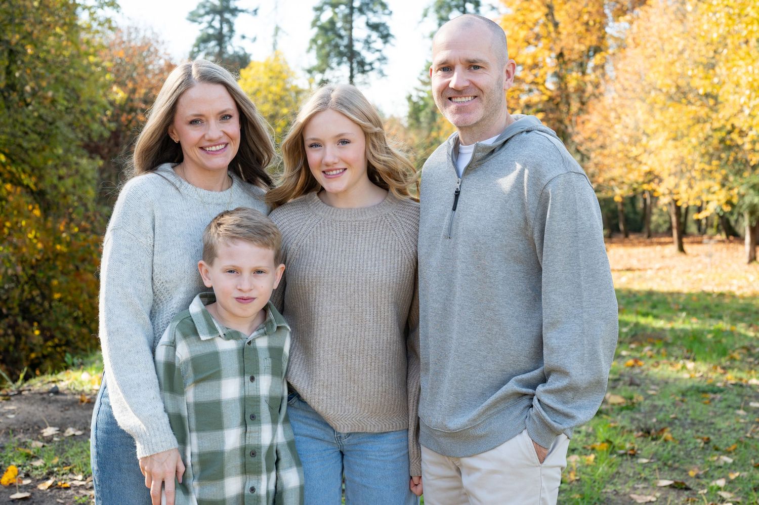 Family poses together in coordinating casual outfits against vibrant fall foliage. Family session. Portrait photography. Oregon.