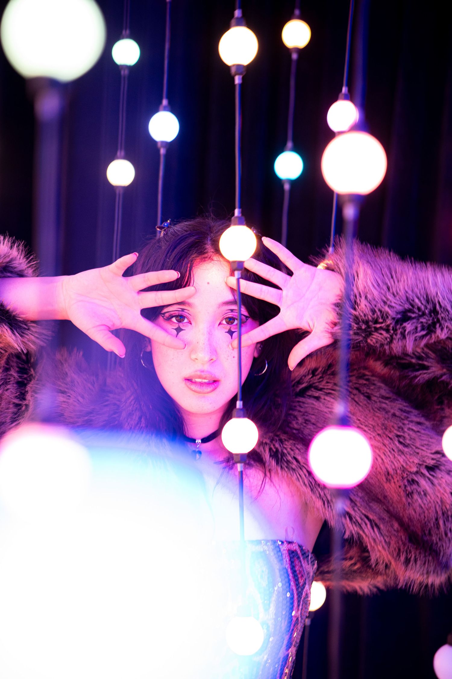 Dramatic pose under hanging orb lights with purple and blue atmospheric lighting. Hopscotch. Portrait Slam.