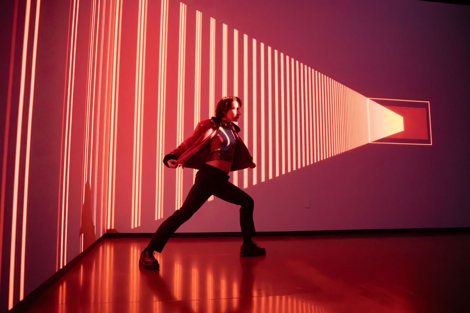 Silhouette moves through red-lit corridor with dramatic vertical light strips. Hopscotch. Portrait Slam.
