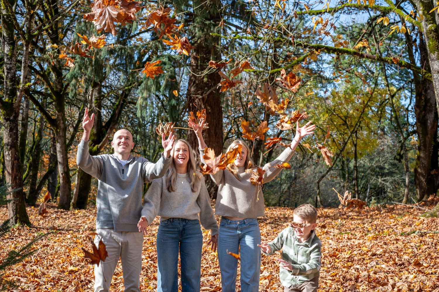 Family enjoying a sunny autumn day together on a leaf-covered trail in the woods. Family session. Portrait photography. Oregon.