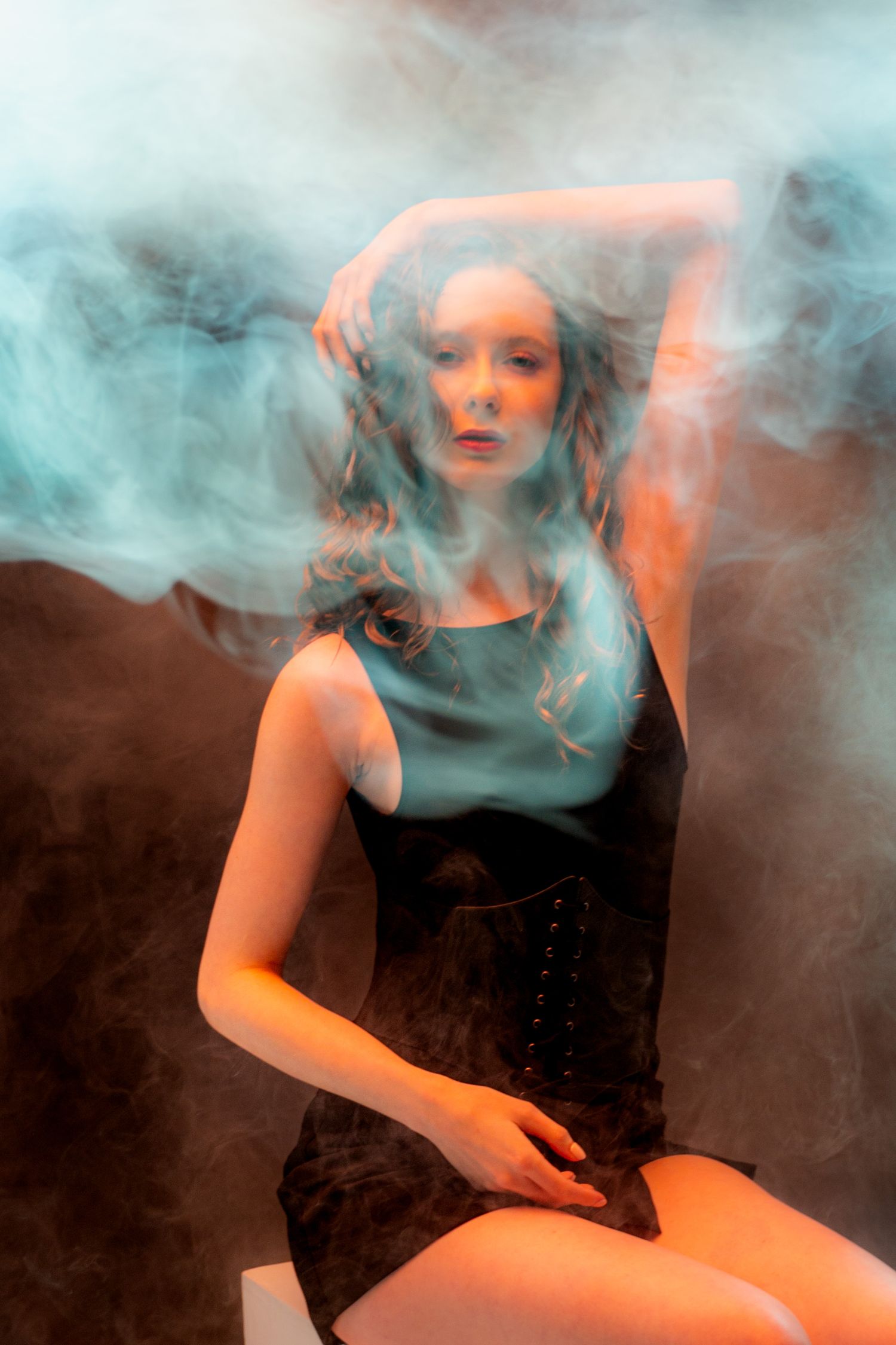Studio photography with mixed lighting creating orange and blue tones through atmospheric smoke. Creative portfolio. Studio. Portrait photog