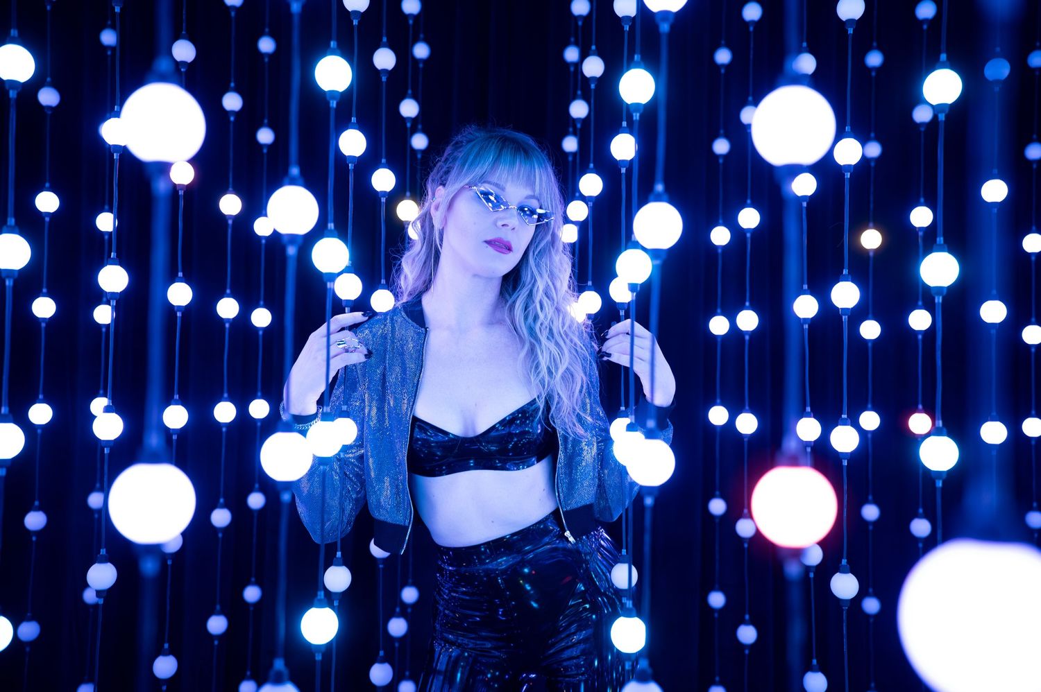 Hanging white orb lights create a magical illuminated backdrop in dark blue space. Hopscotch. Portrait Slam.