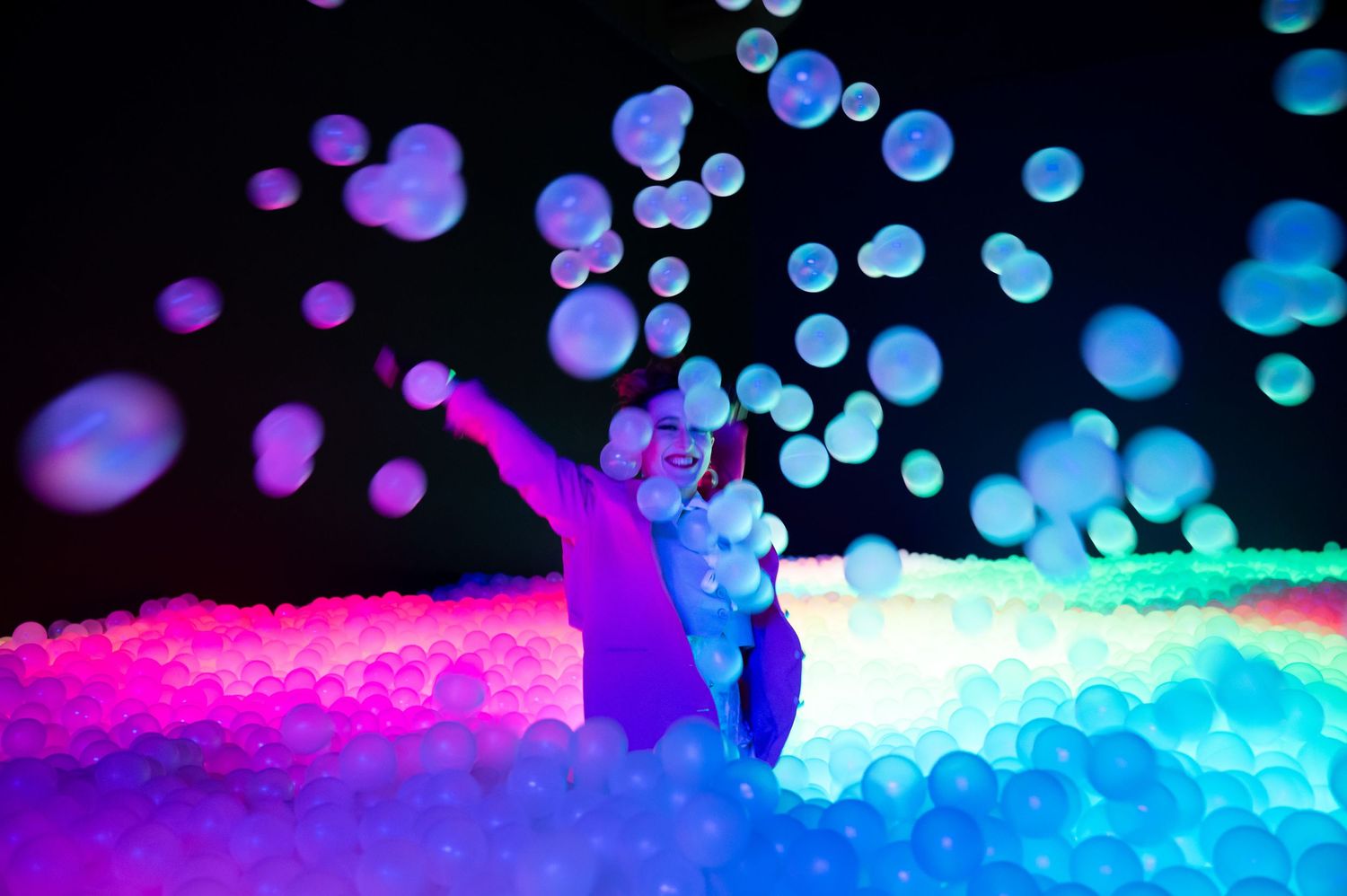 Silhouetted dancer performs against colorful bokeh lights and glowing ground effects. Hopscotch. Portrait Slam.