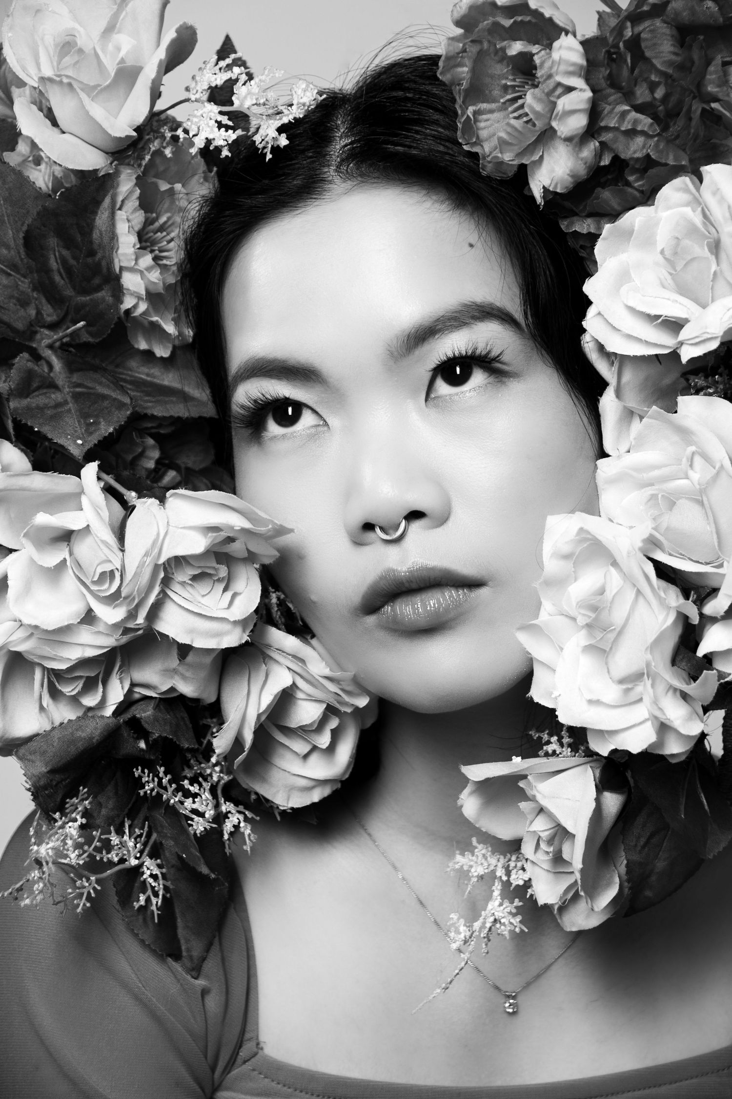 Artistic black and white portrait with white roses framing the composition.