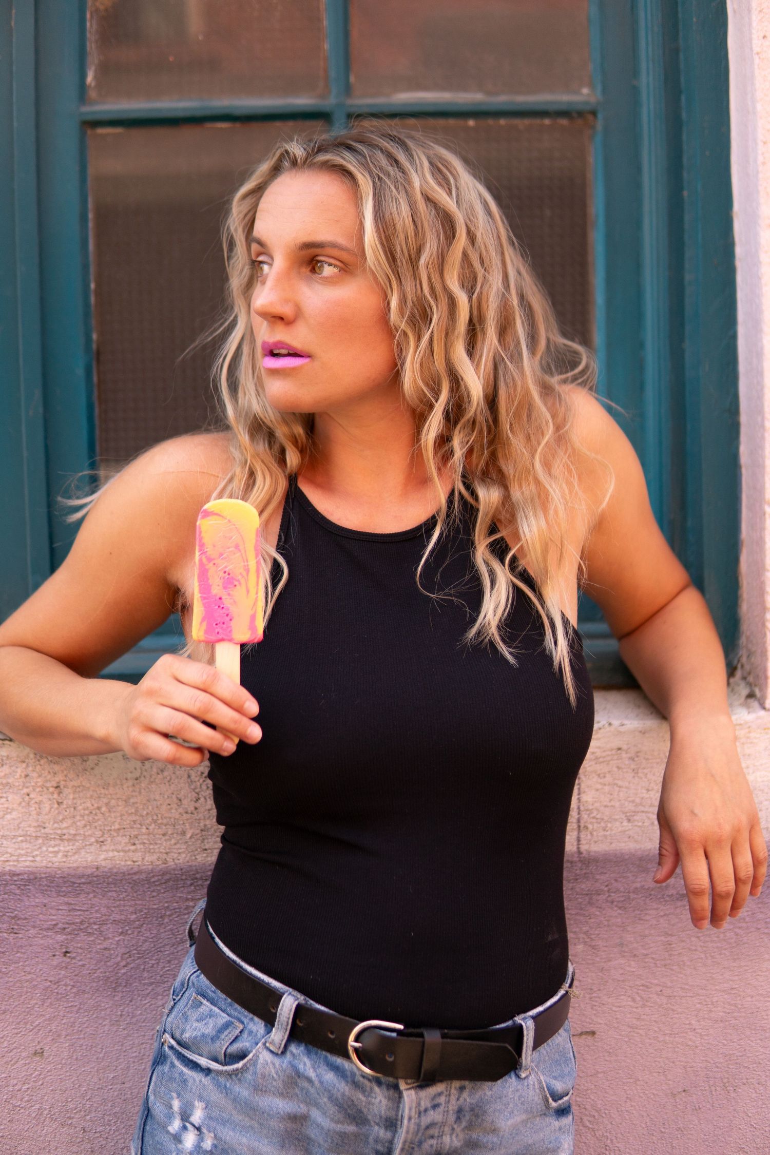 A series of four similar photos showing someone in a black tank top and jeans posing casually against a wall.