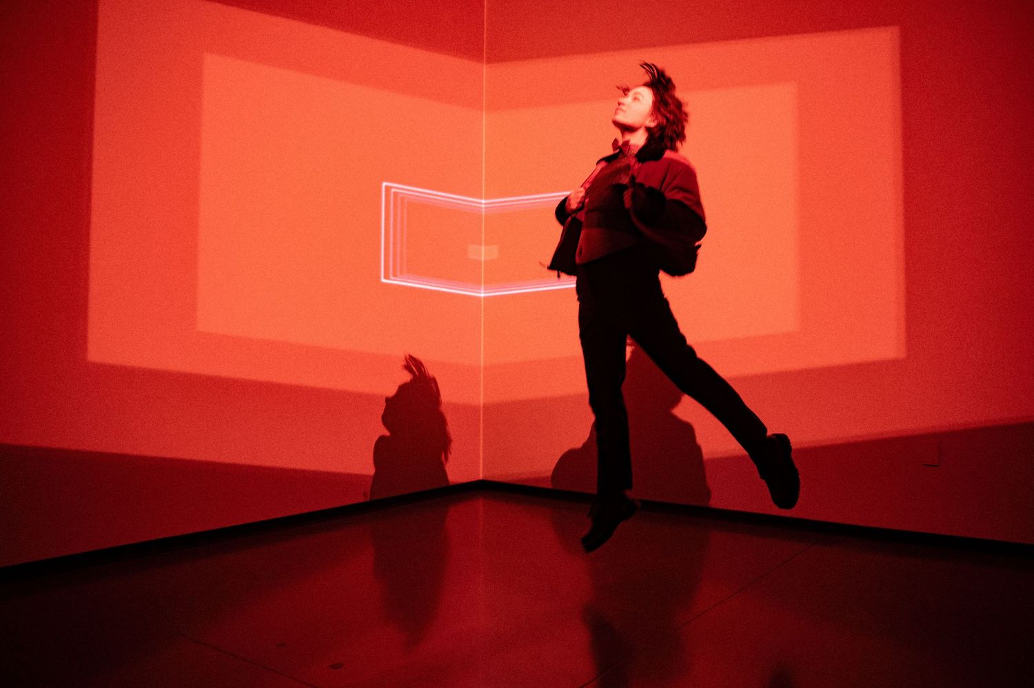 Silhouette performs dynamic movements in red-lit geometric space. Hopscotch. Portrait Slam.