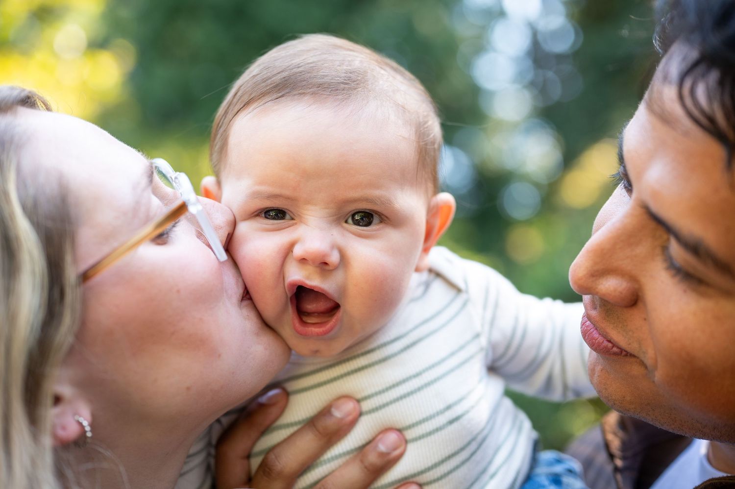 Close-up of tender family moment outdoors with natural sunlit background. Family session. Portrait photography. Oregon.