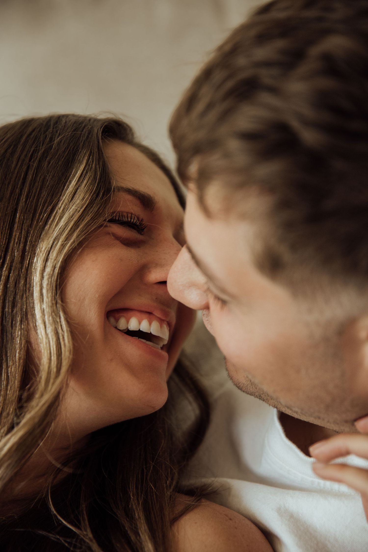 Close-up of a laughing couple nearly kissing, capturing a joyful and intimate romantic moment.